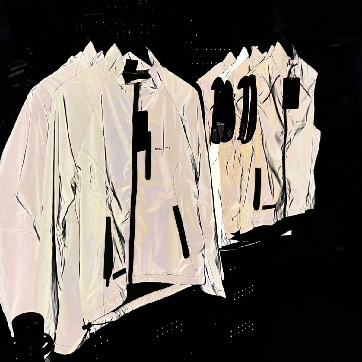 Bodylite Unisex Fully Reflective Jacket 01303-ALL SIZES and gilet hanging up in the dark showing how reflective they are.