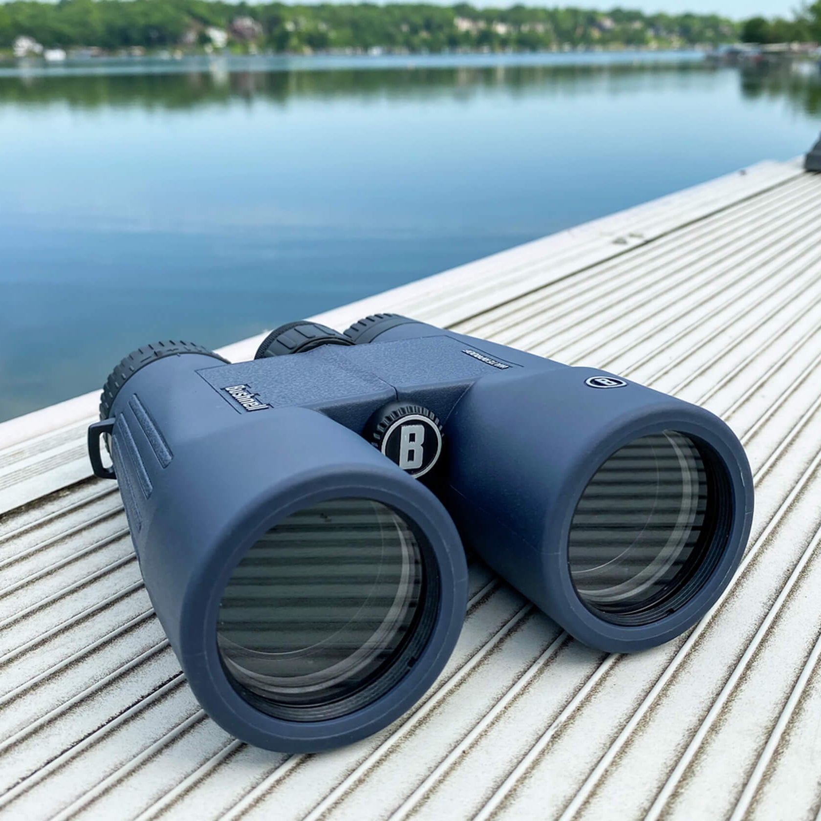Blue Bushnell H2O Waterproof Binoculars on a wooden dock by a lake