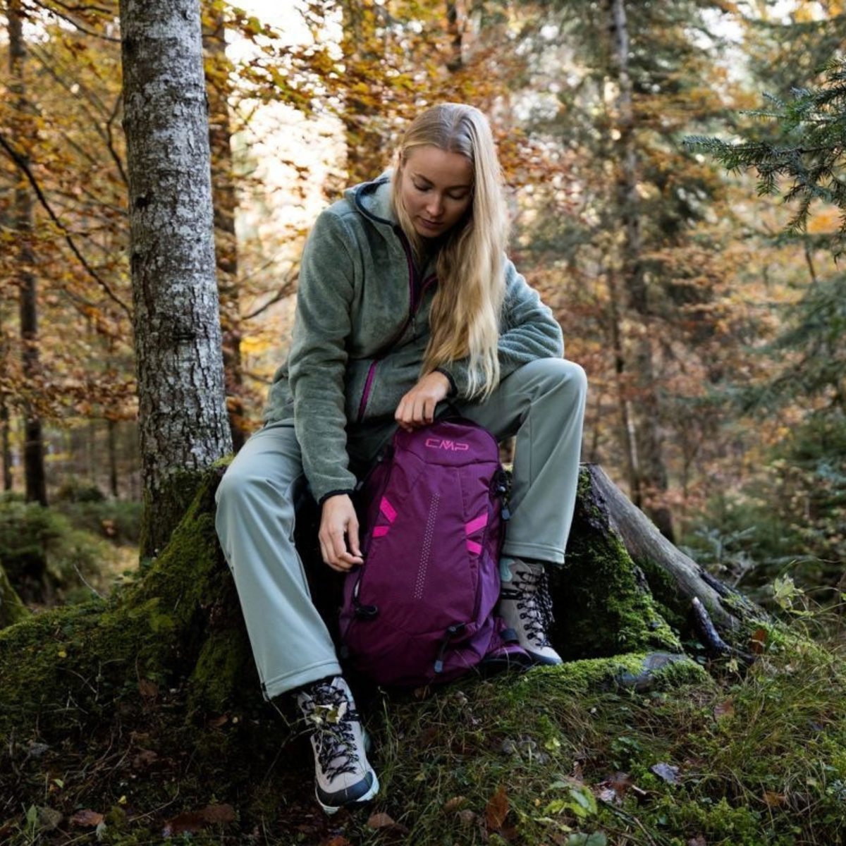 Woman sitting on a tree stump, in a forest, looking in her CMP Laredo Trekking Daypack 22L C910 Amaranto 3V17957