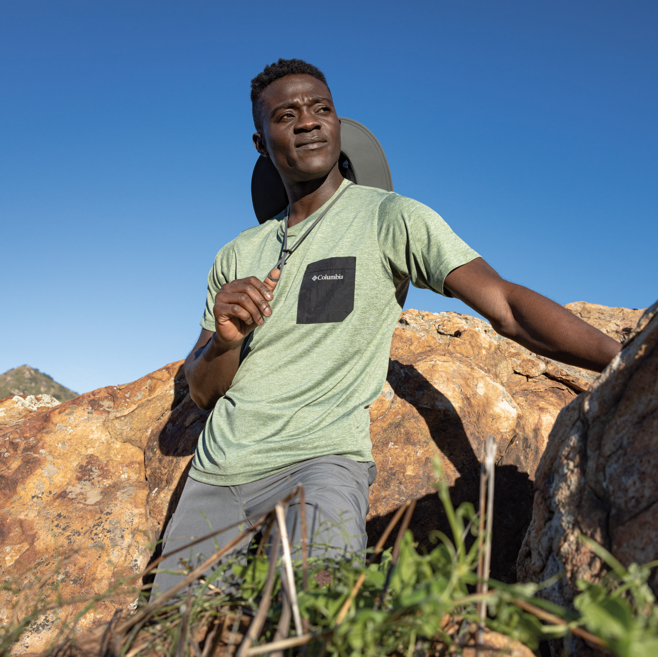 Man standing on rocky terrain with clear blue sky wearing Columbia Unisex Bora Bora UPF50 Booney Sun Hat Grill 028 1447091