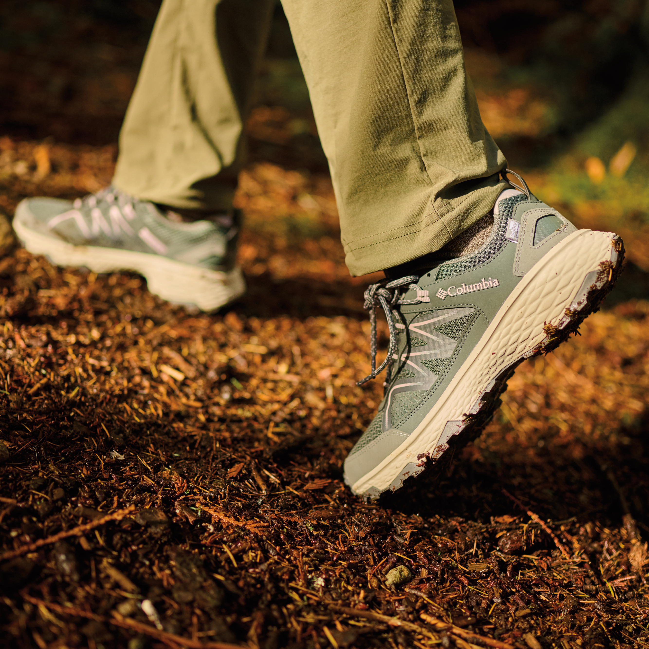 Woman wearing Columbia Women's Peakfreak Rush Outdry Waterproof Trail Shoes Grill Vapor 028 2108431 on a dirt trail in the sun