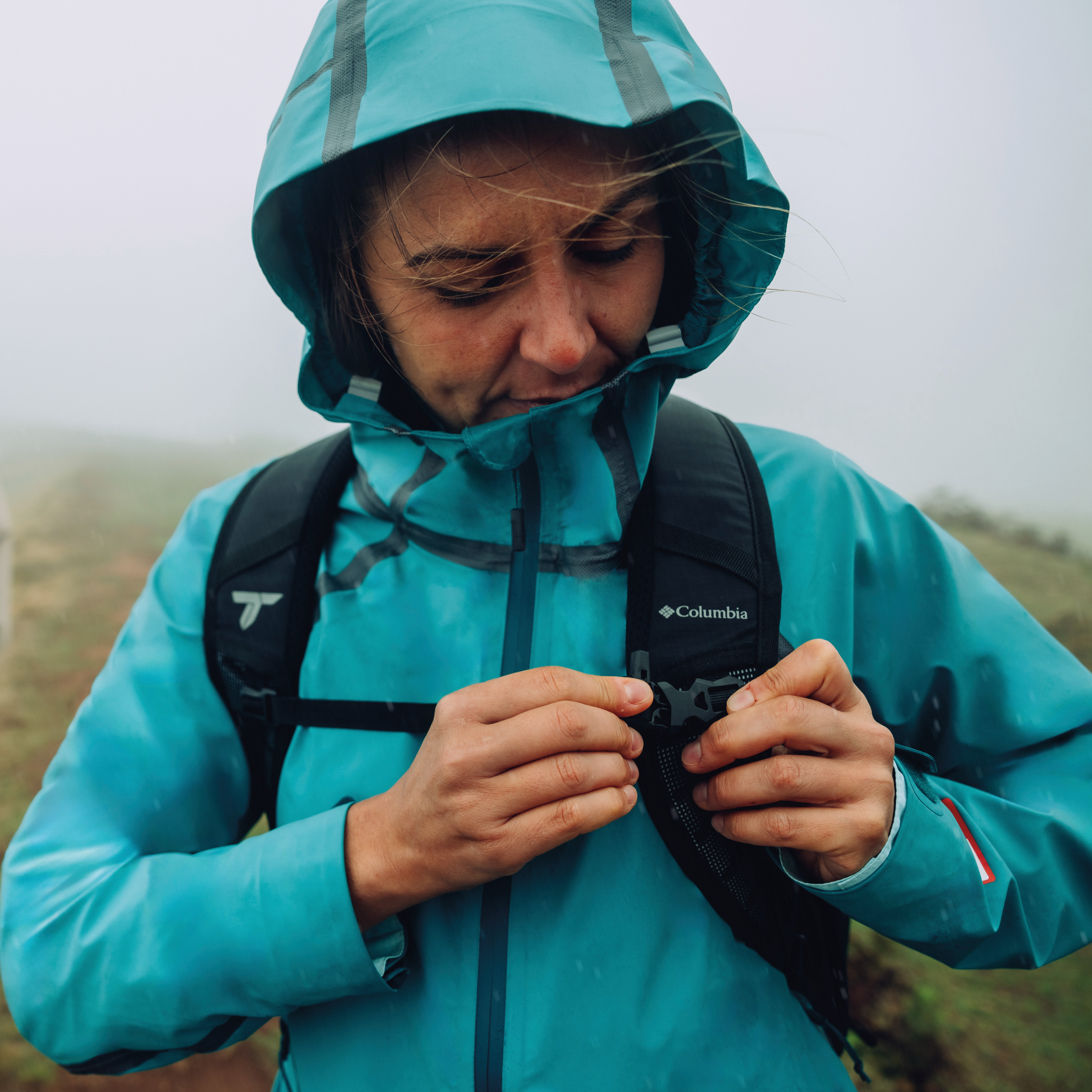 Woman wearing Columbia Women's Reign No Shine Outdry Extreme Waterproof Jacket River Blue 364 2116293 on a foggy outdoor trail