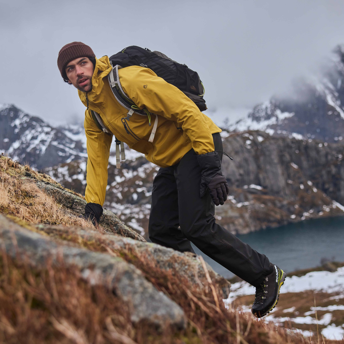 Man wearing Craghoppers Men's Steall Pro Thermo Waterproof Trousers Black 800 CMW847 climbing in a snowy, mountain setting
