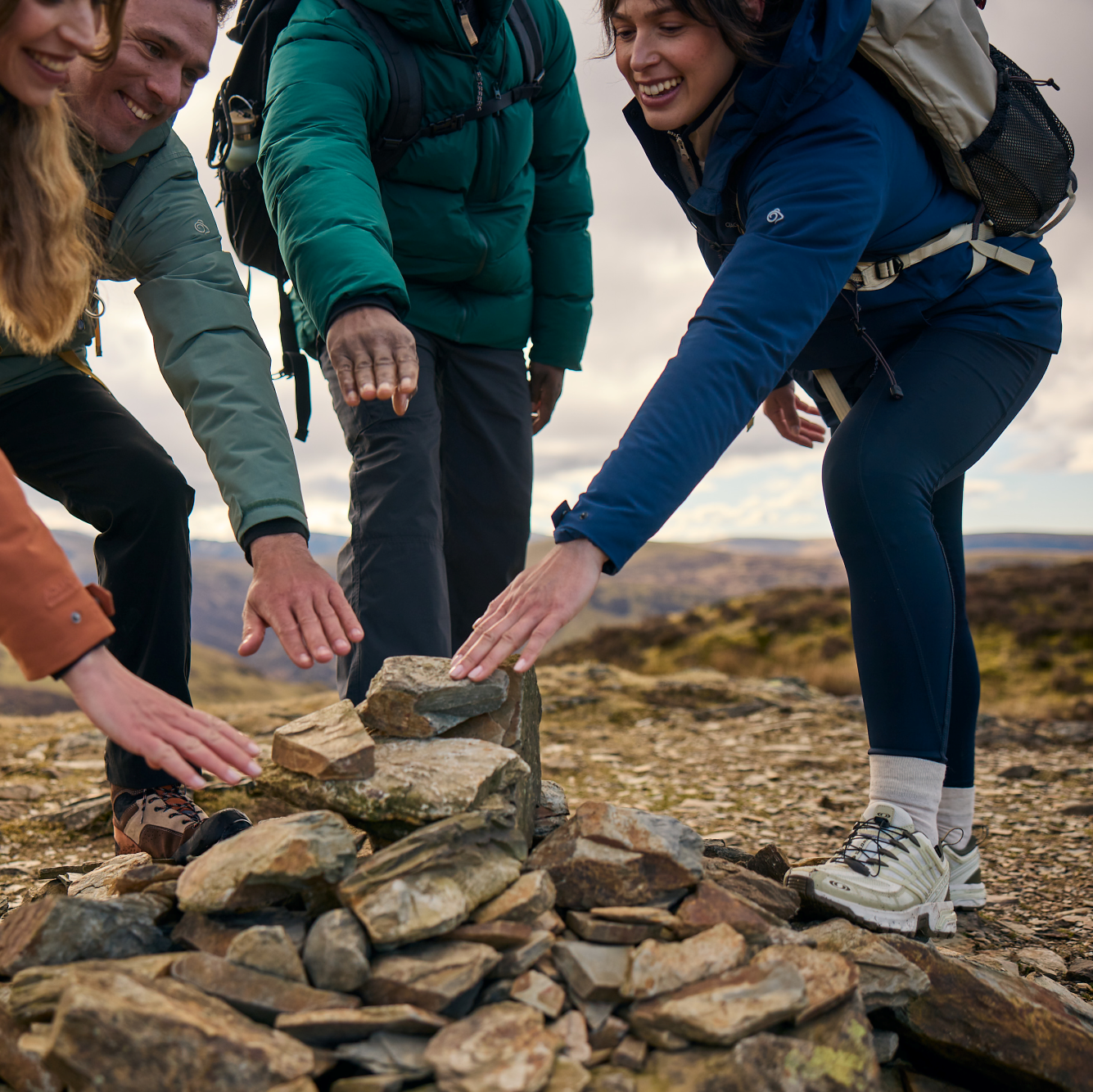 Woman wearing Craghoppers Women's Kiwi Pro Leggings Blue Navy 7V1 CWJ1335 touching the summit marker on a mountain hike