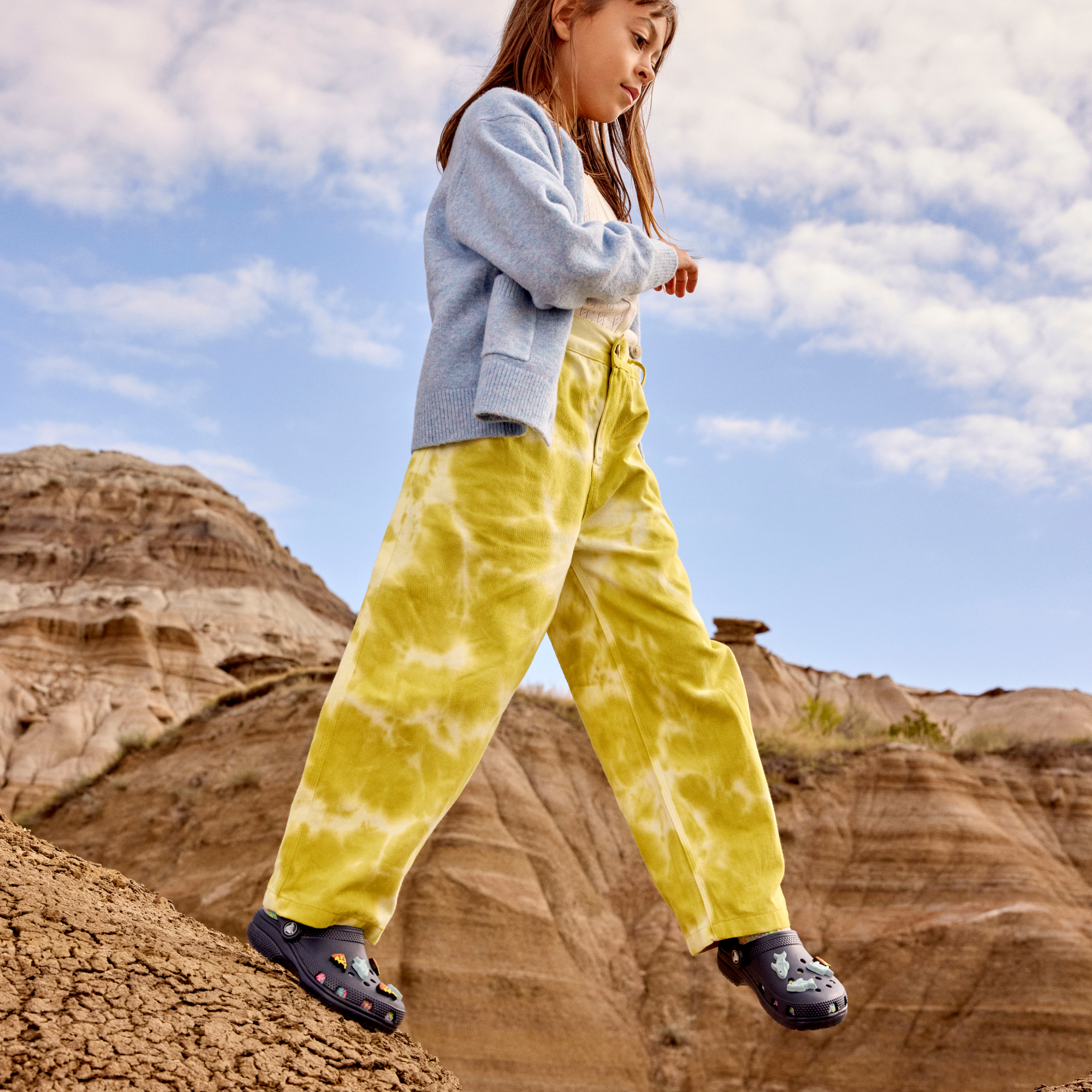 Young girl wearing Crocs Classic Clogs Junior Navy 410 206991 walking in a desert setting
