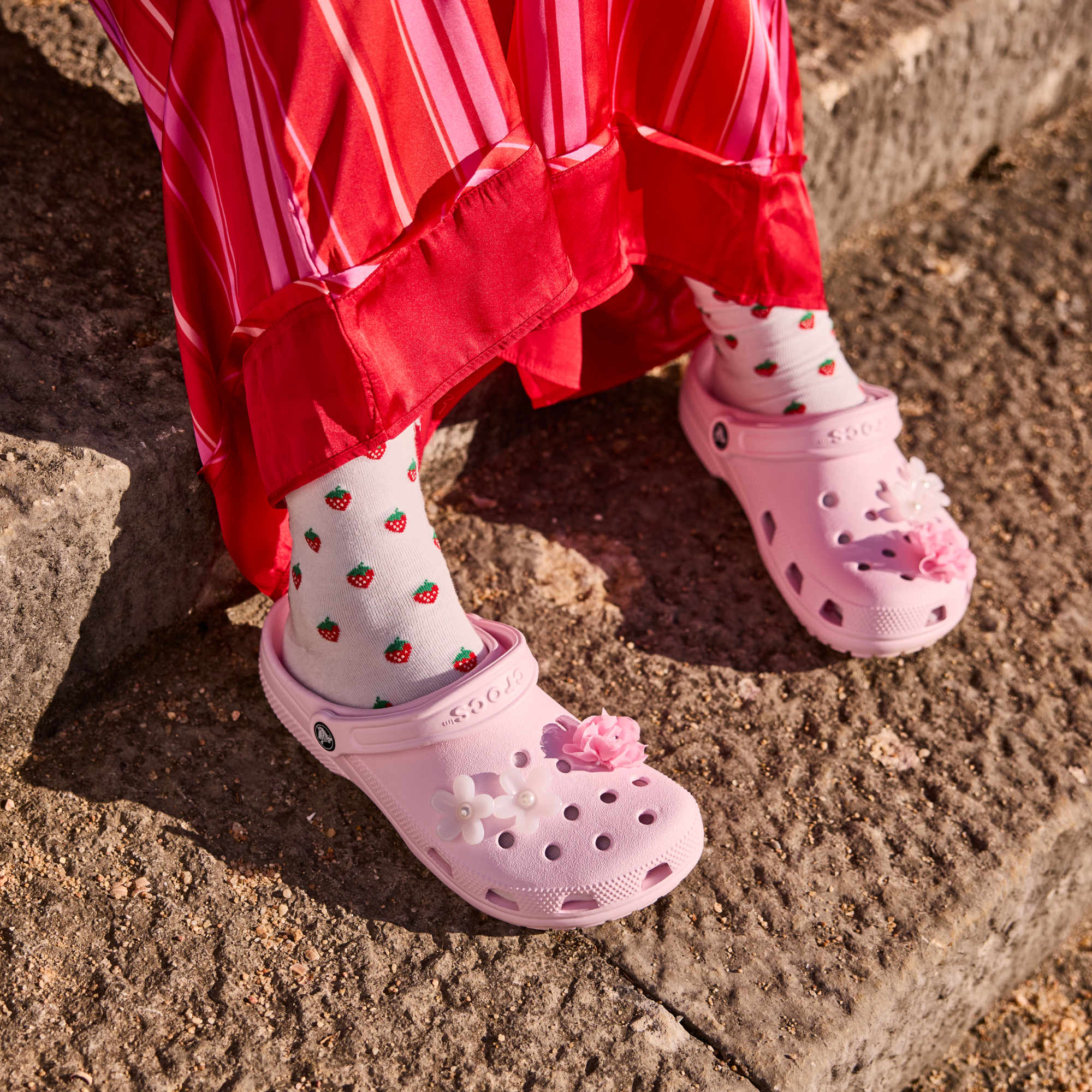 Woman wearing Crocs Unisex Classic Clogs Pink Milk 6ZW 10001 on stone steps