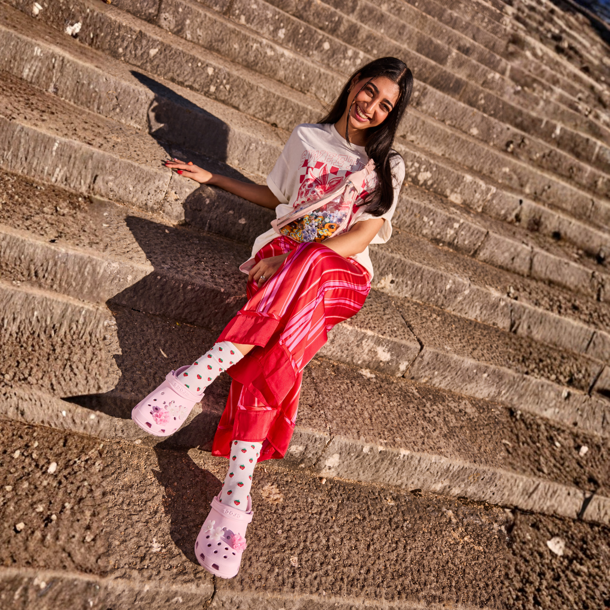 Woman wearing Crocs Unisex Classic Clogs Pink Milk 6ZW 10001 sitting on stone steps