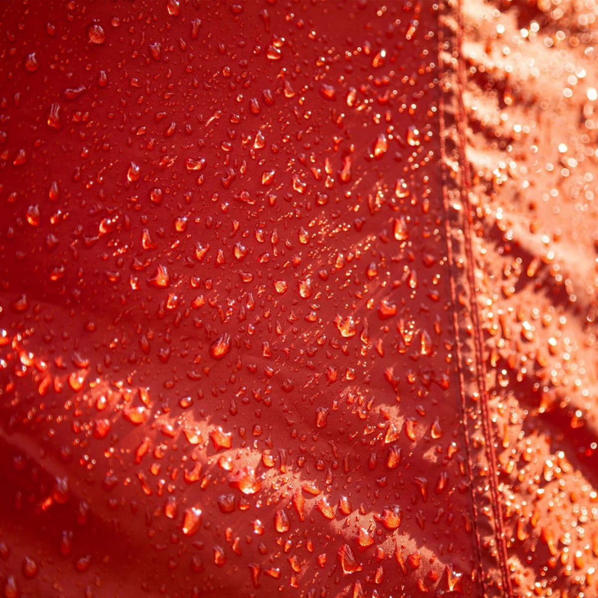 Close-up of a red tent surface with water droplets