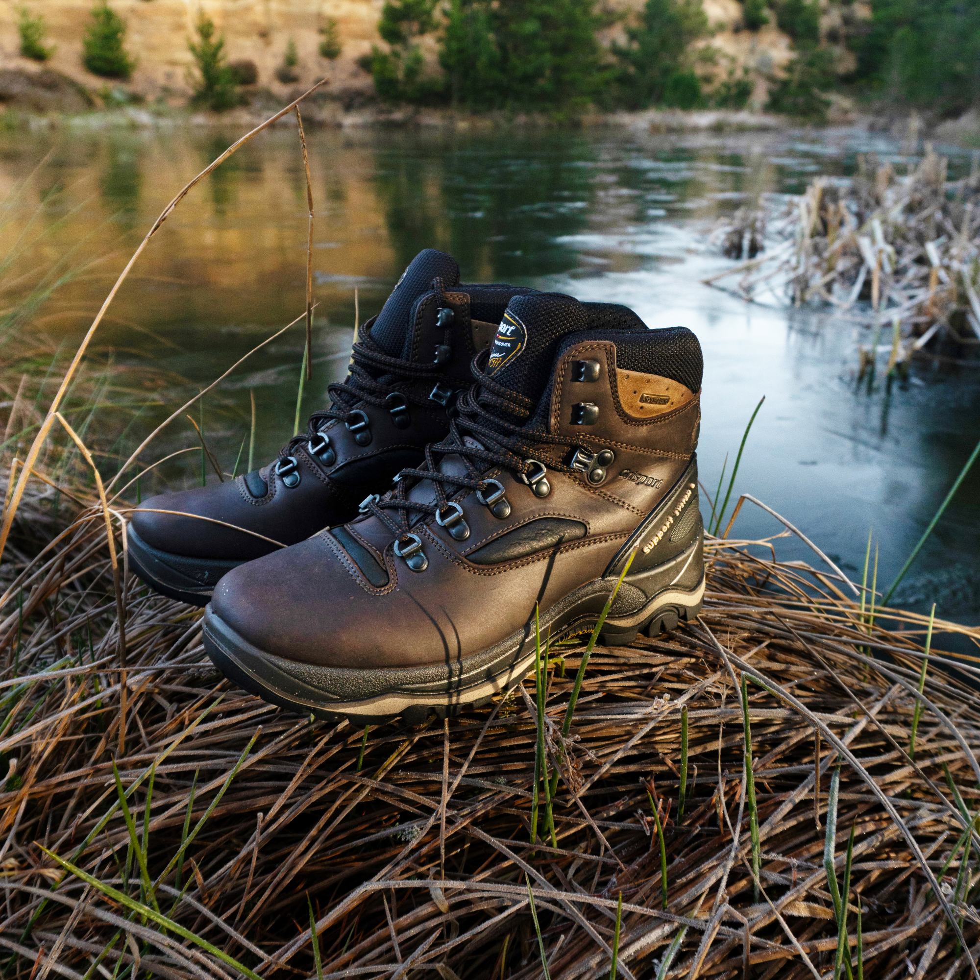Pair of Grisport Men's Quatro Waterproof Hillwalking Boots Brown CMG614 on grass near a body of water with trees in the background