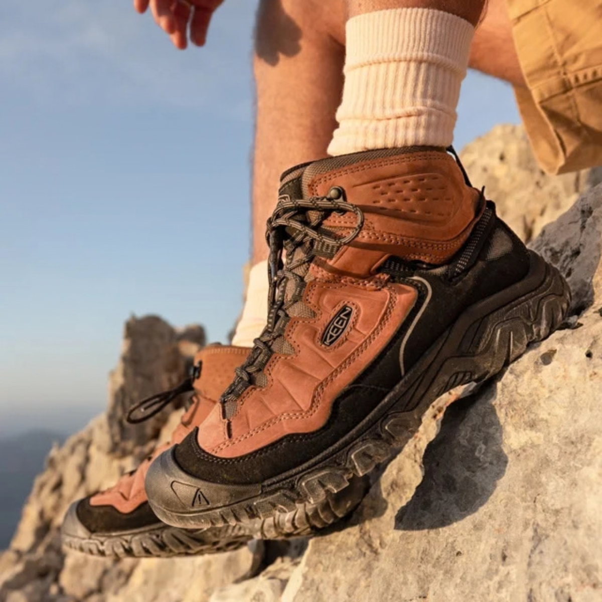 Person sitting on a rocky outcrop wearing Keen Men's Targhee IV Waterproof Mid Trail Boots Wide Fit Bison Black 1029002