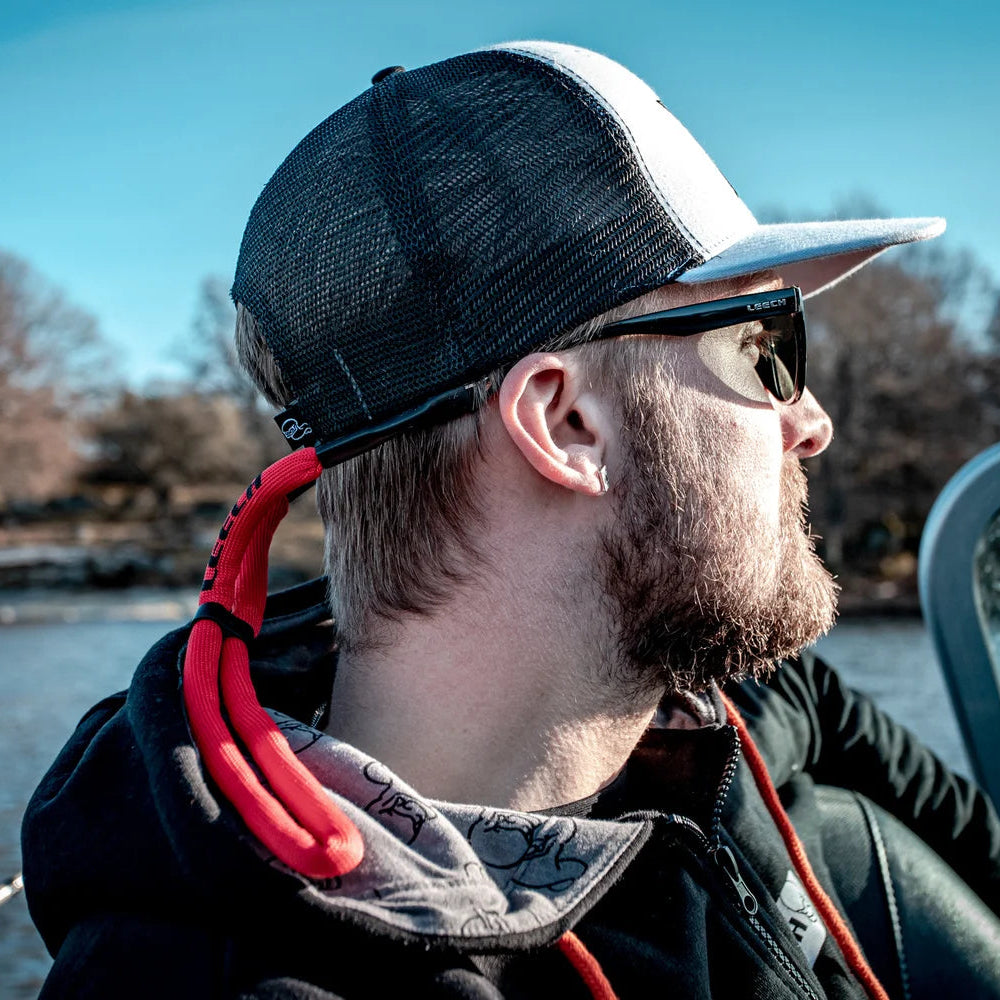 Man wearing Leech Neoprene Floating Eyewear Strap Red PL-FS2107 sitting on a boat