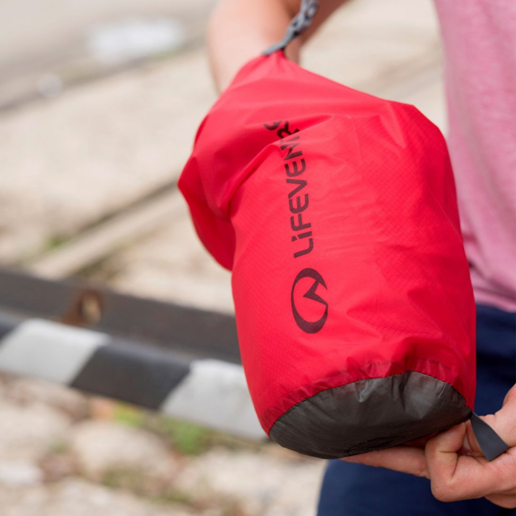 Lifeventure Ultralight Dry Bag 2L Red 59610 held by a person outdoors.