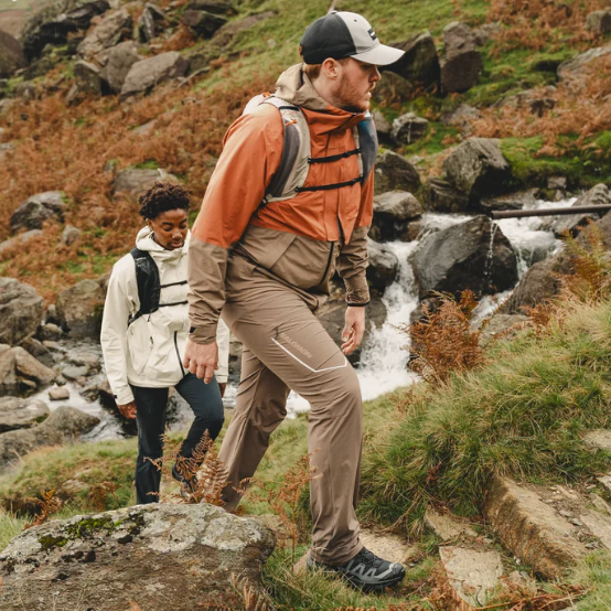 Man wearing Salomon Men's X Ultra 360 Gore-Tex Mid Trail Boots Black Magnet Pewter L47447600 hiking in the mountains beside a stream with a woman hiking behind him