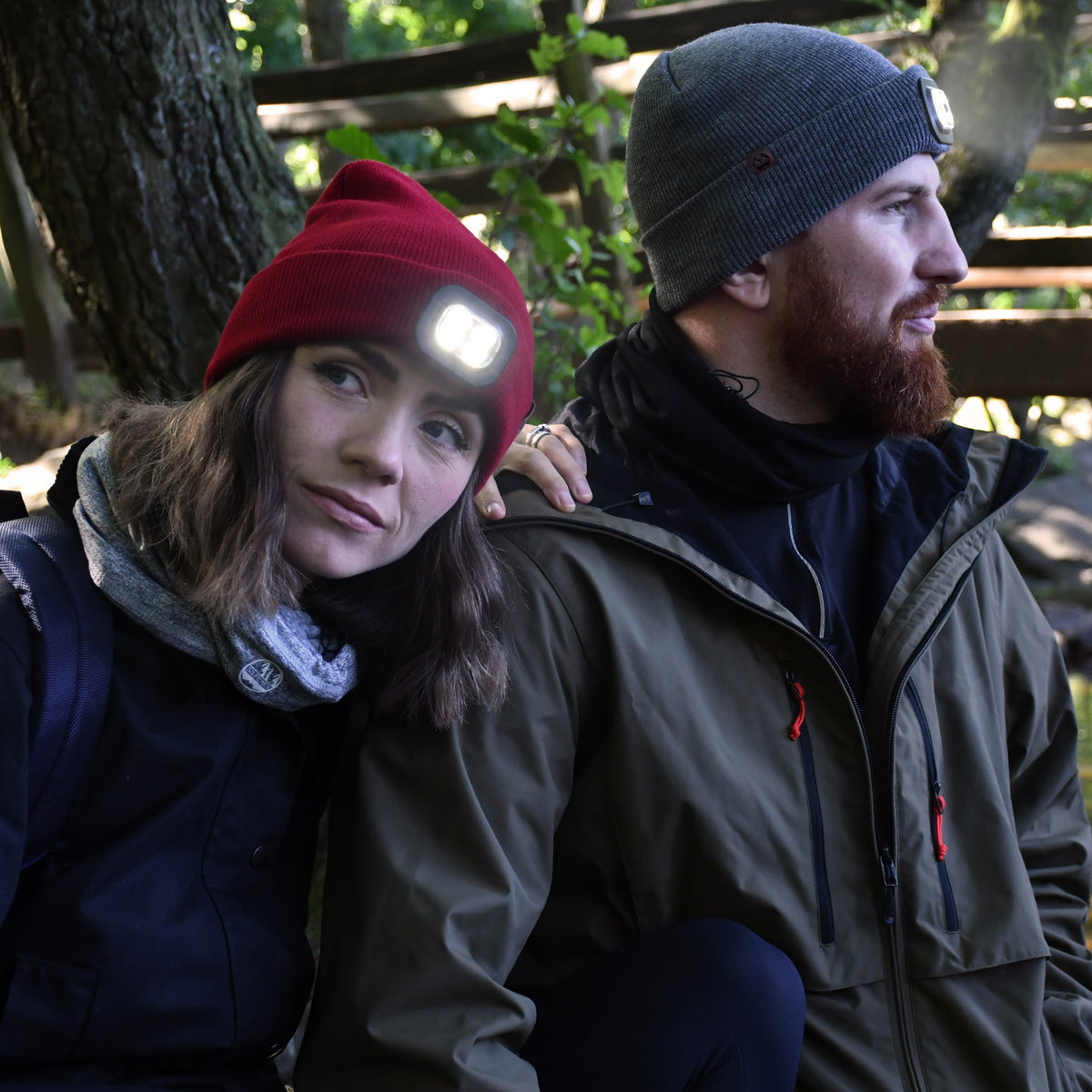 Two people sitting by a stream with surrounded by nature. Man wearing Six Peaks Unisex LED Lighted Beanie Hat Grey SIH0004
