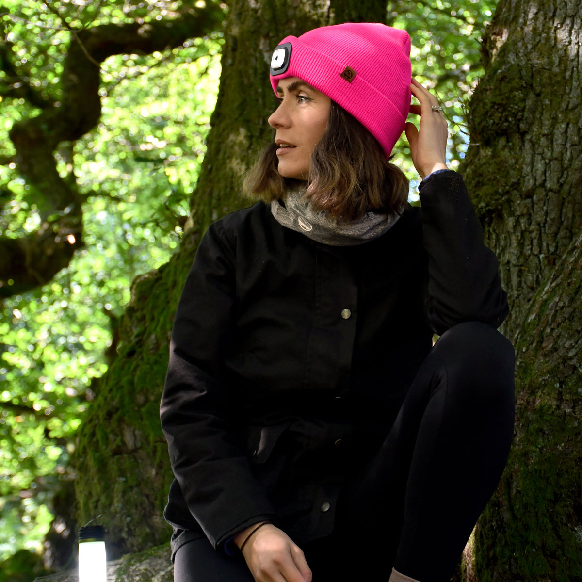 Woman wearing Six Peaks Unisex LED Lighted Beanie Hat Pink SIH0004 sitting against a tree