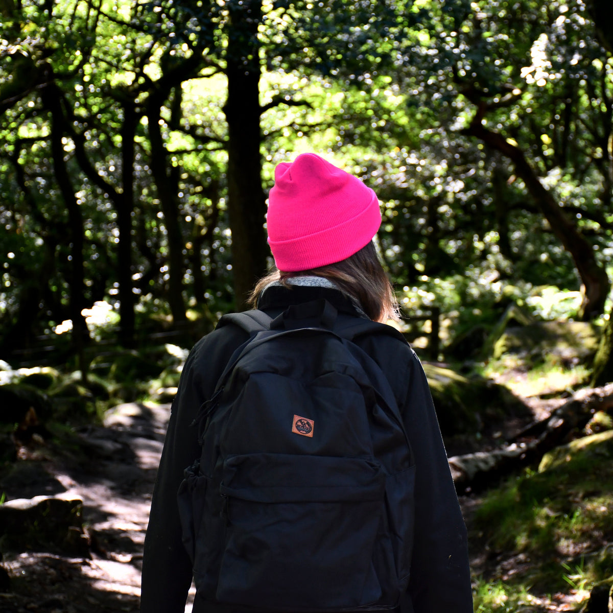 Person wearing a Six Peaks Unisex LED Lighted Beanie Hat Pink SIH0004 and dark jacket walking through a forest
