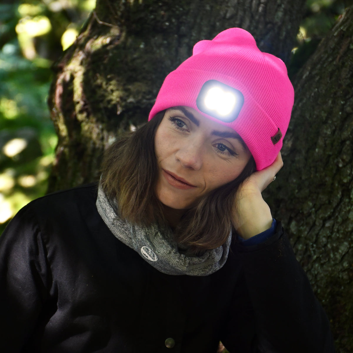 Person wearing a Six Peaks Unisex LED Lighted Beanie Hat Pink SIH0004, standing in a forest.
