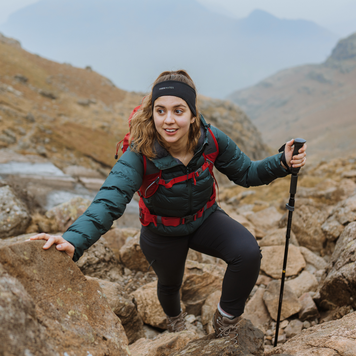 Person hiking on rocky terrain with mountains in the background using Trekmates Fold Lock Hiking Pole Black TM-008701