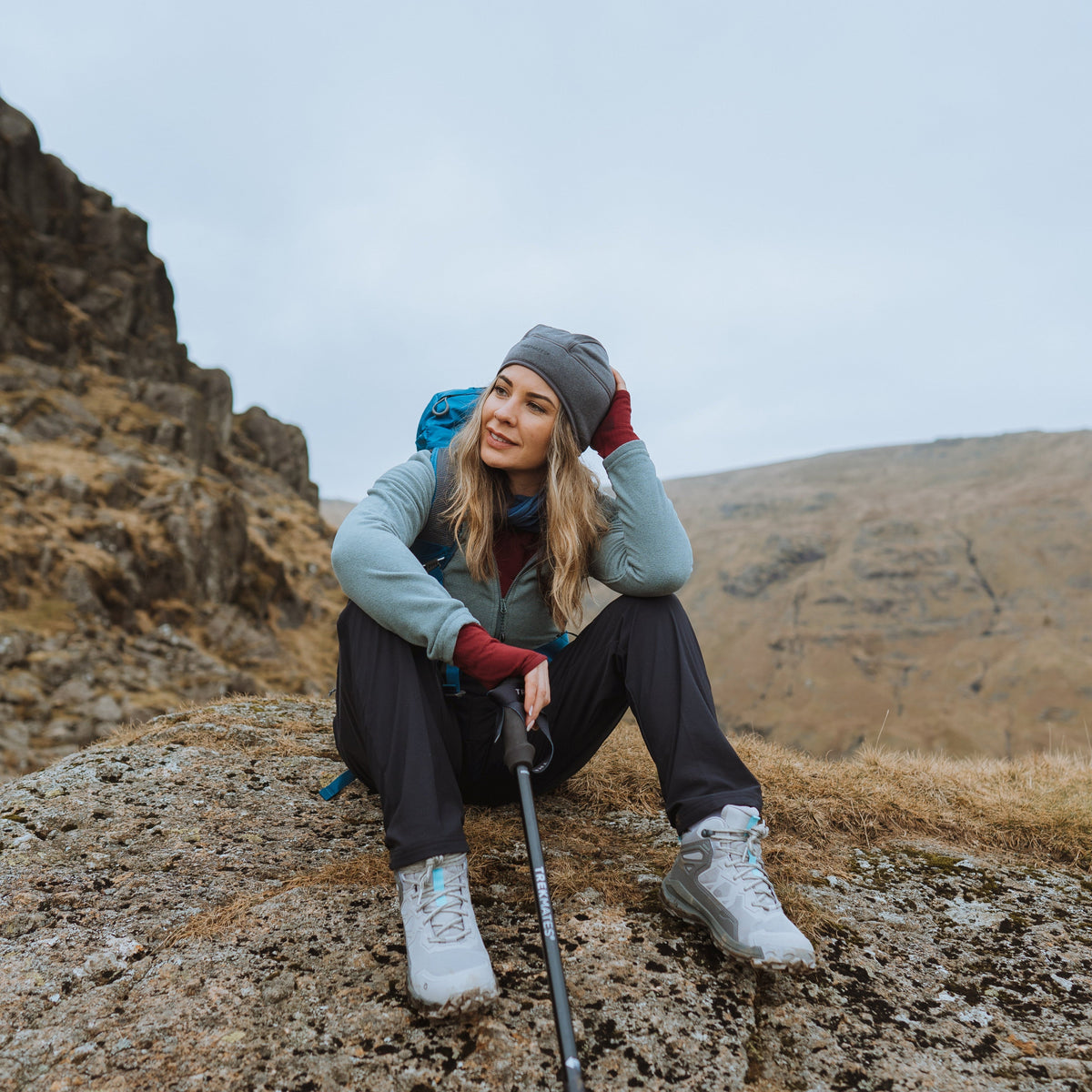 Woman sitting on a rock with Trekmates Hiker Shock Single Pole Black TM-008705 in a mountainous landscape