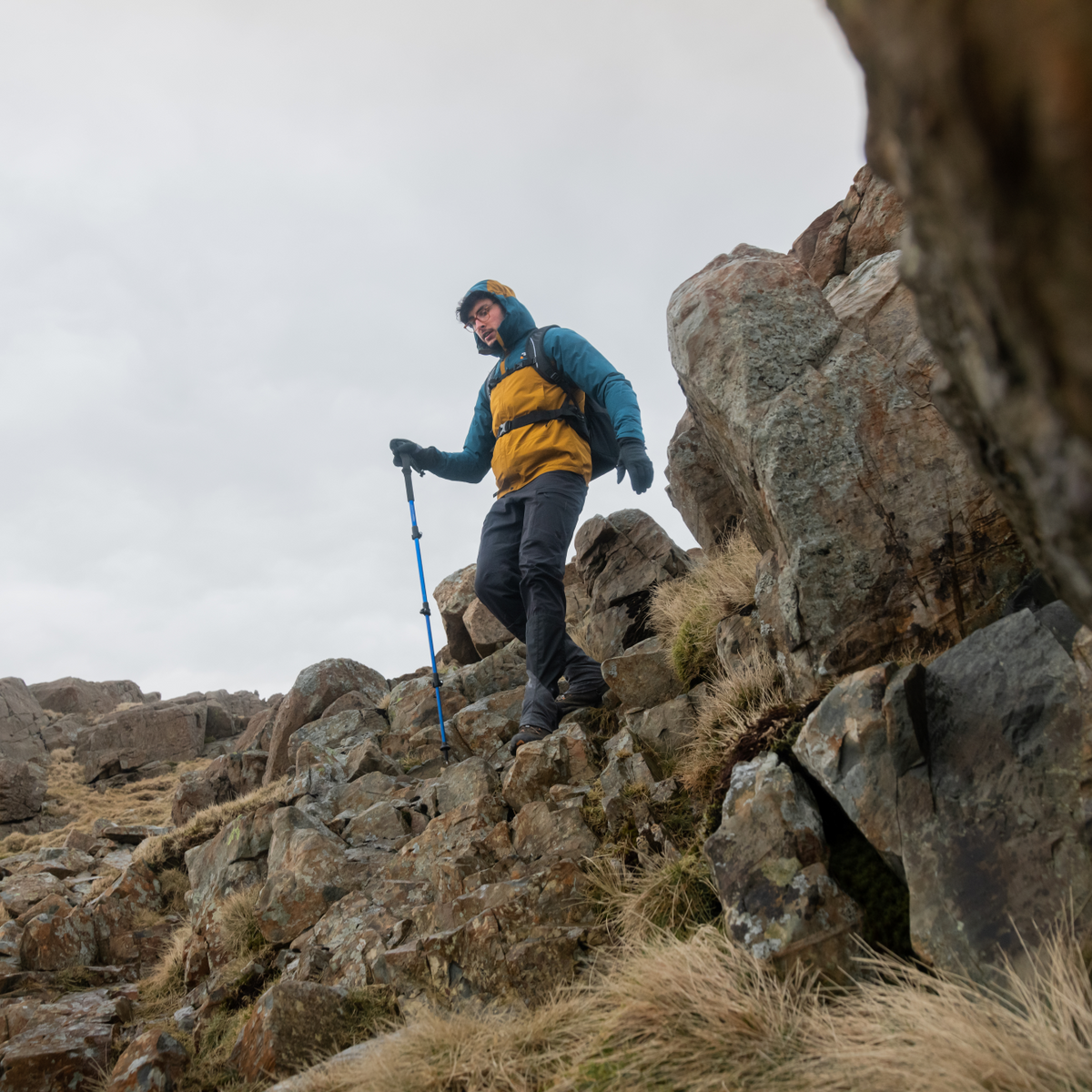 Person hiking on a rocky mountain with a backpack and Trekmates Trekker Compact Single Pole Cobalt TM-008702