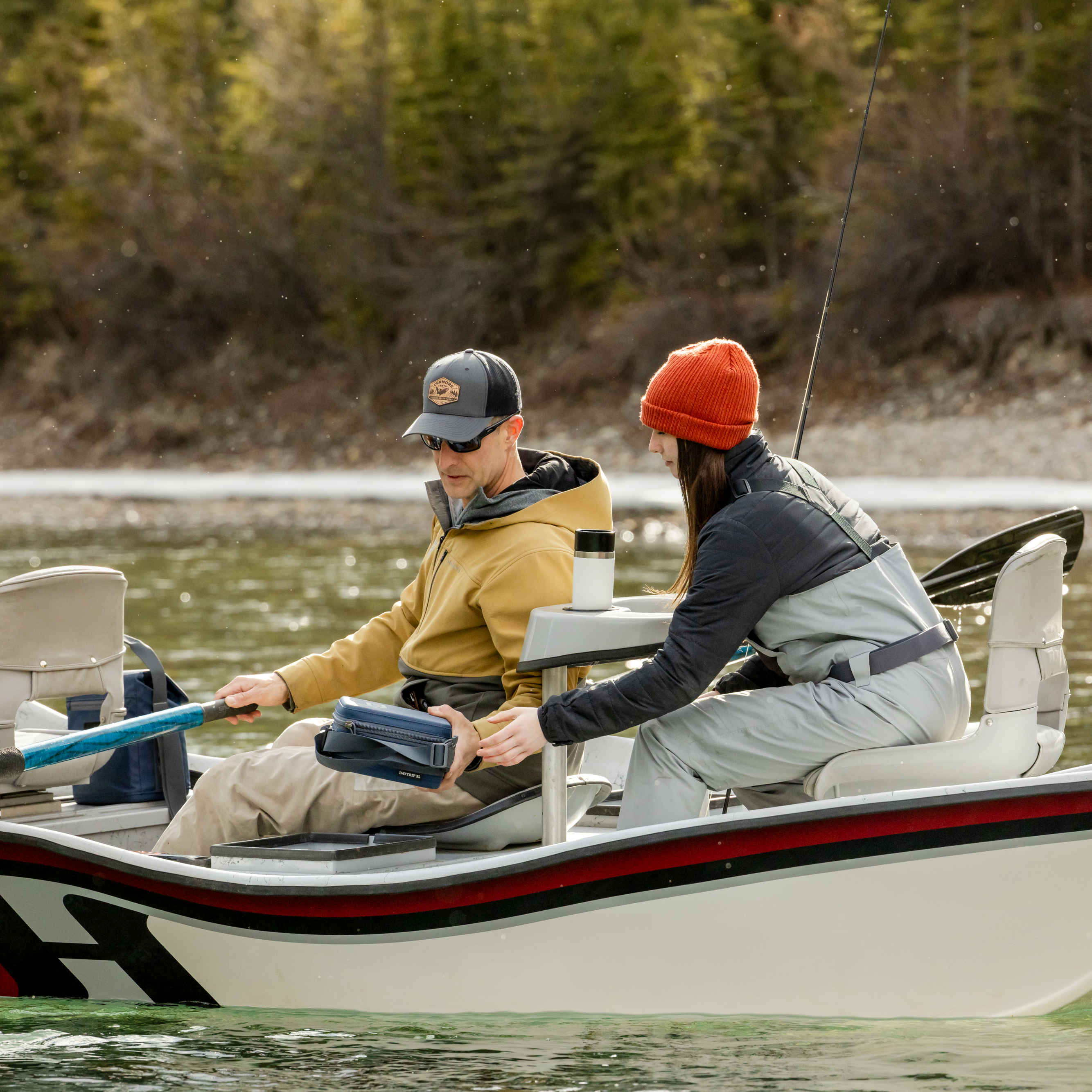 Young girl and her Dad fishing off a boat on a lake with a white Yeti rambler travel bottle with commuter lid sitting in a cupholder