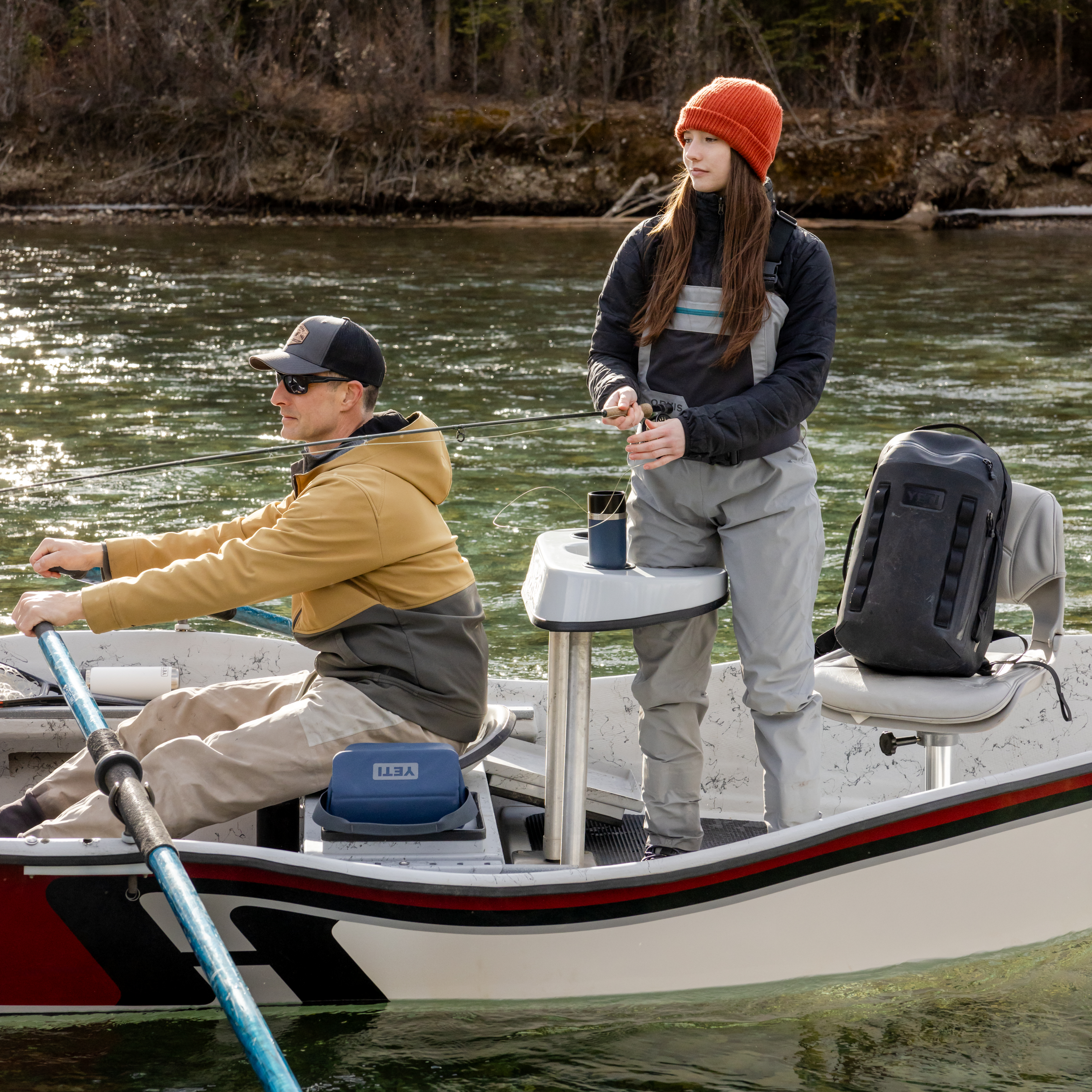Young girl and her dad fishing off a boat on a lake. Navy Yeti rambler travel bottle with commuter lid sitting in a cup holder