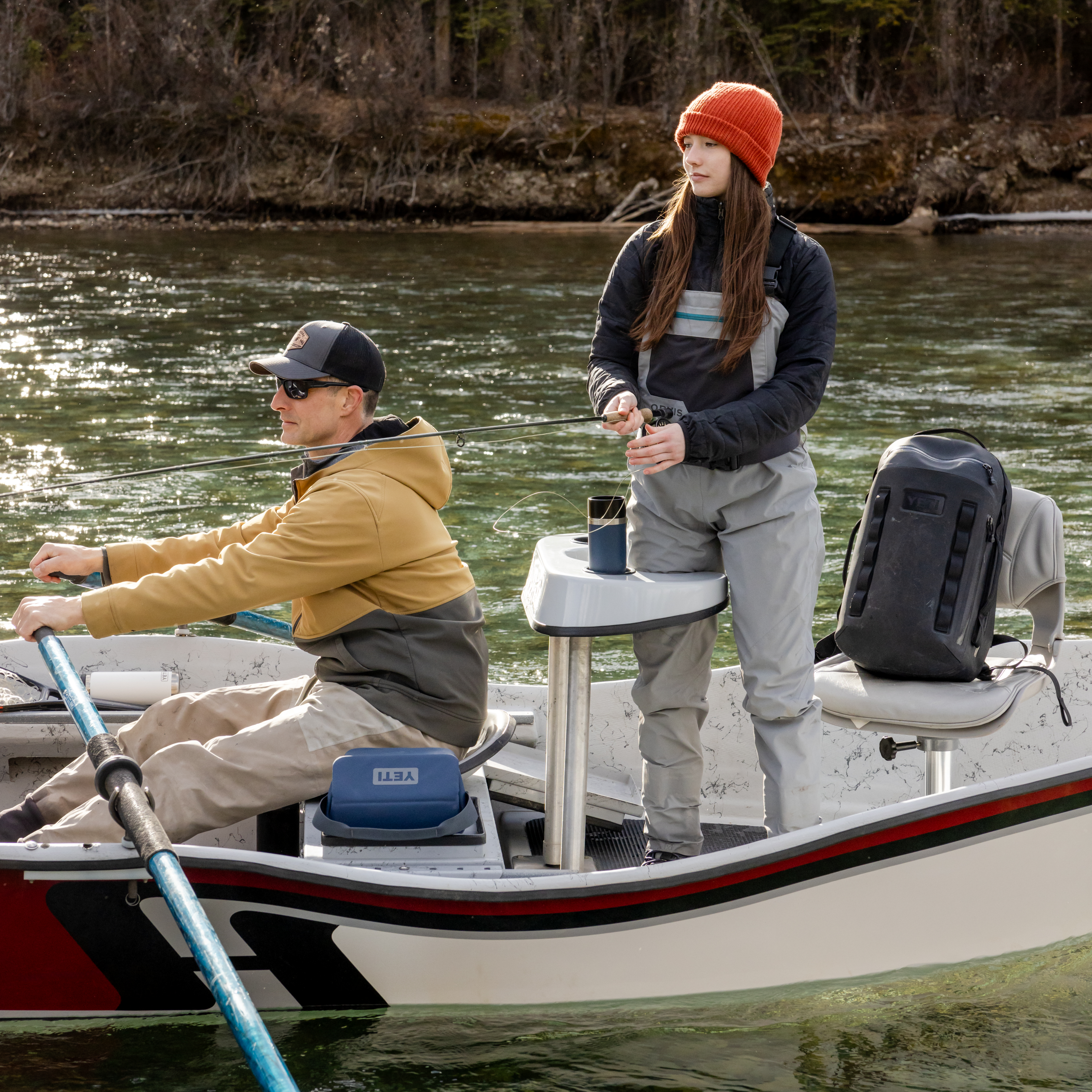 Young girl and her dad fishing from a boat on a lake with a navy Yeti travel bottle with commuter lid sitting in a cupholder