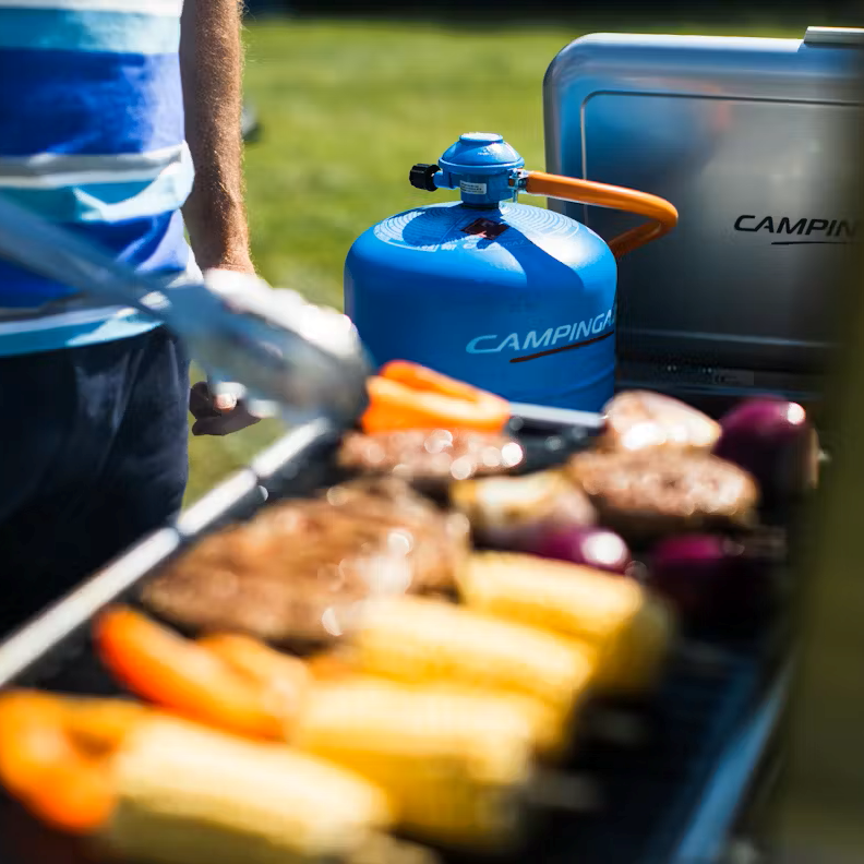 Camping Gaz 907 Gas Refill Only GAS907 connected to a camping stove while a man cooks on the stove