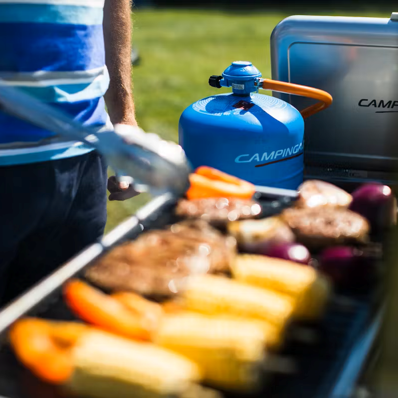 Man cooking on a camping stove connected to Camping Gaz 907 Cylinder Bottle Gas GAS907CYL