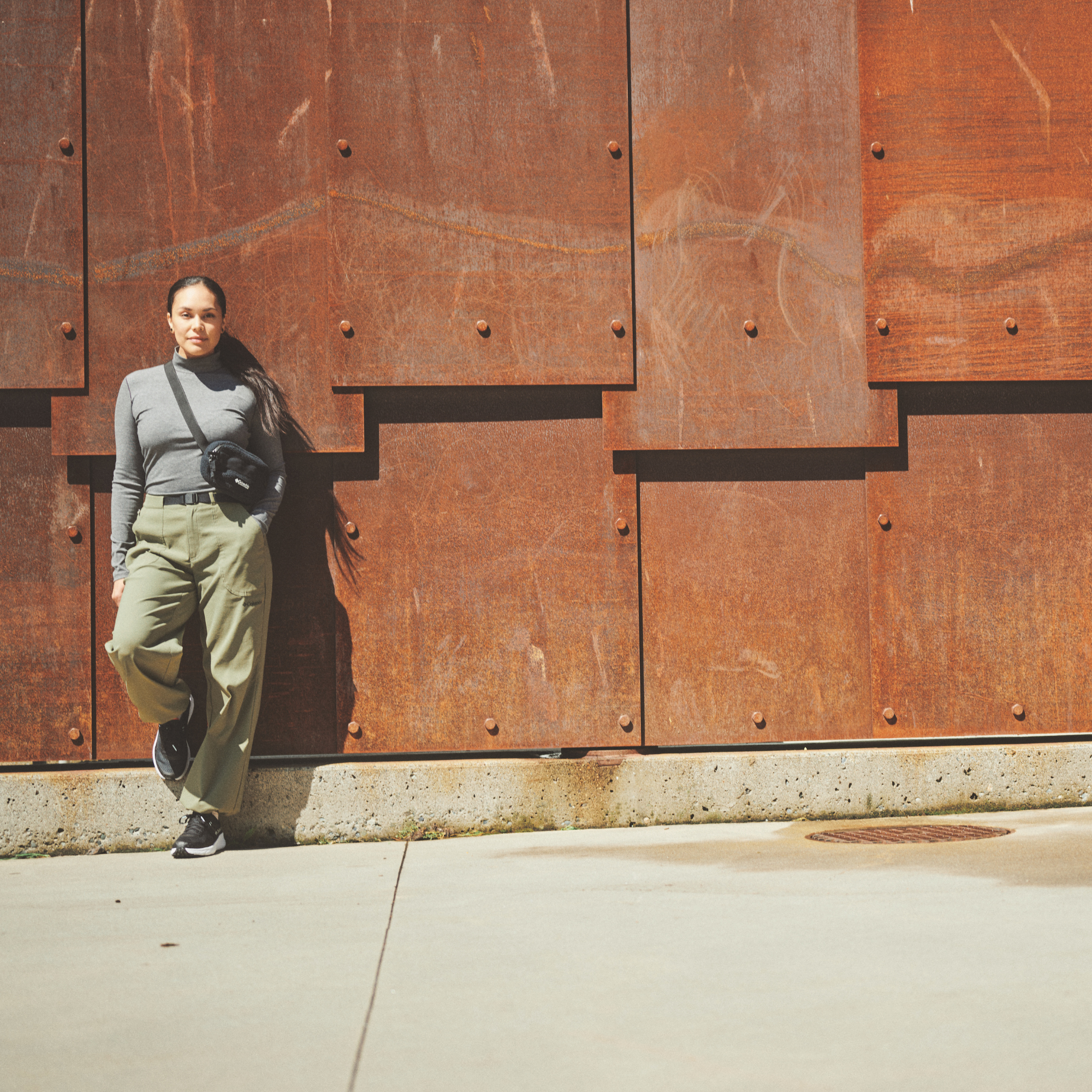 Woman standing against a metal wall wearing a Columbia Helvetia II Sherpa Hip Pack Black 010 2094541