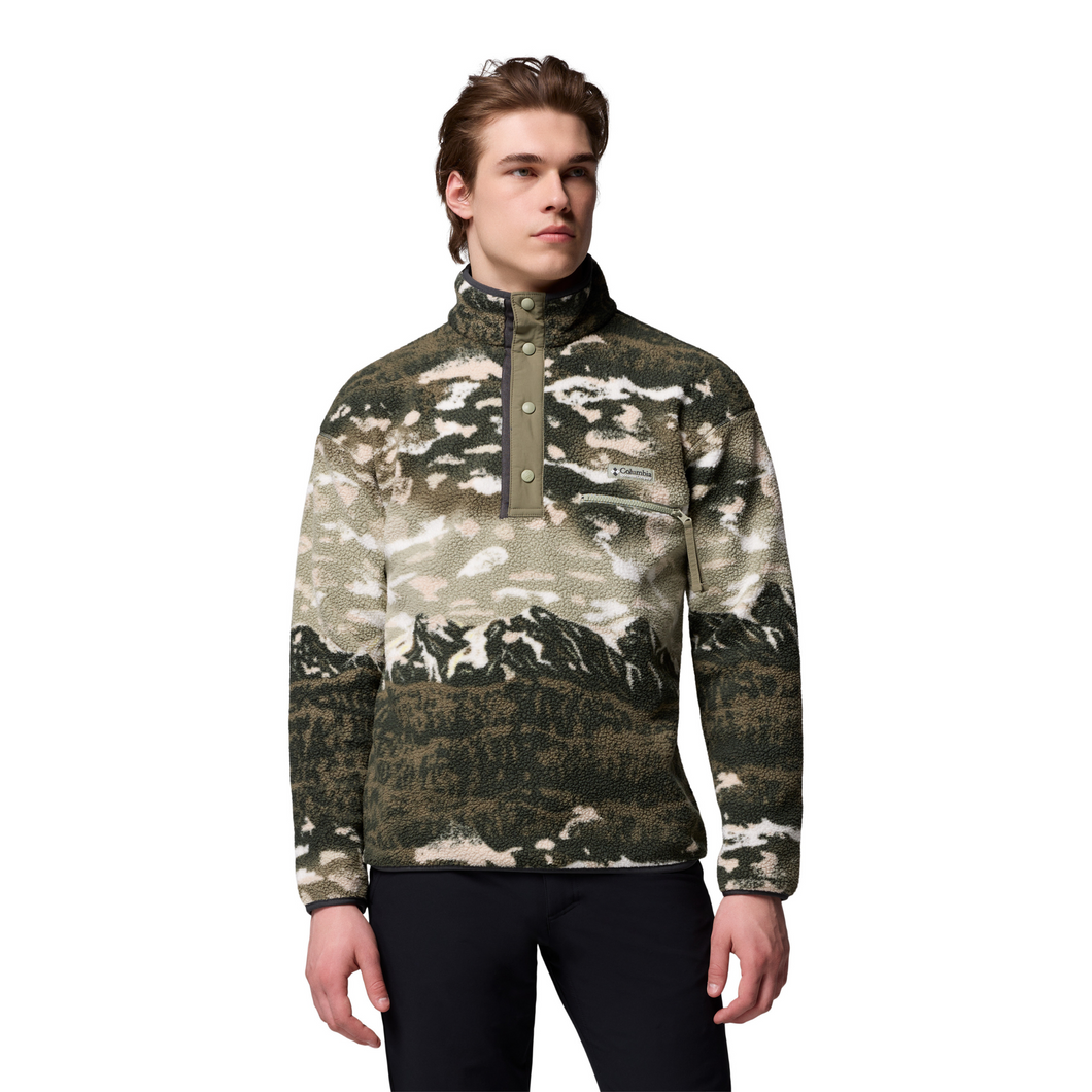 Man wearing a camouflage-patterned pullover with mountain design on a white background