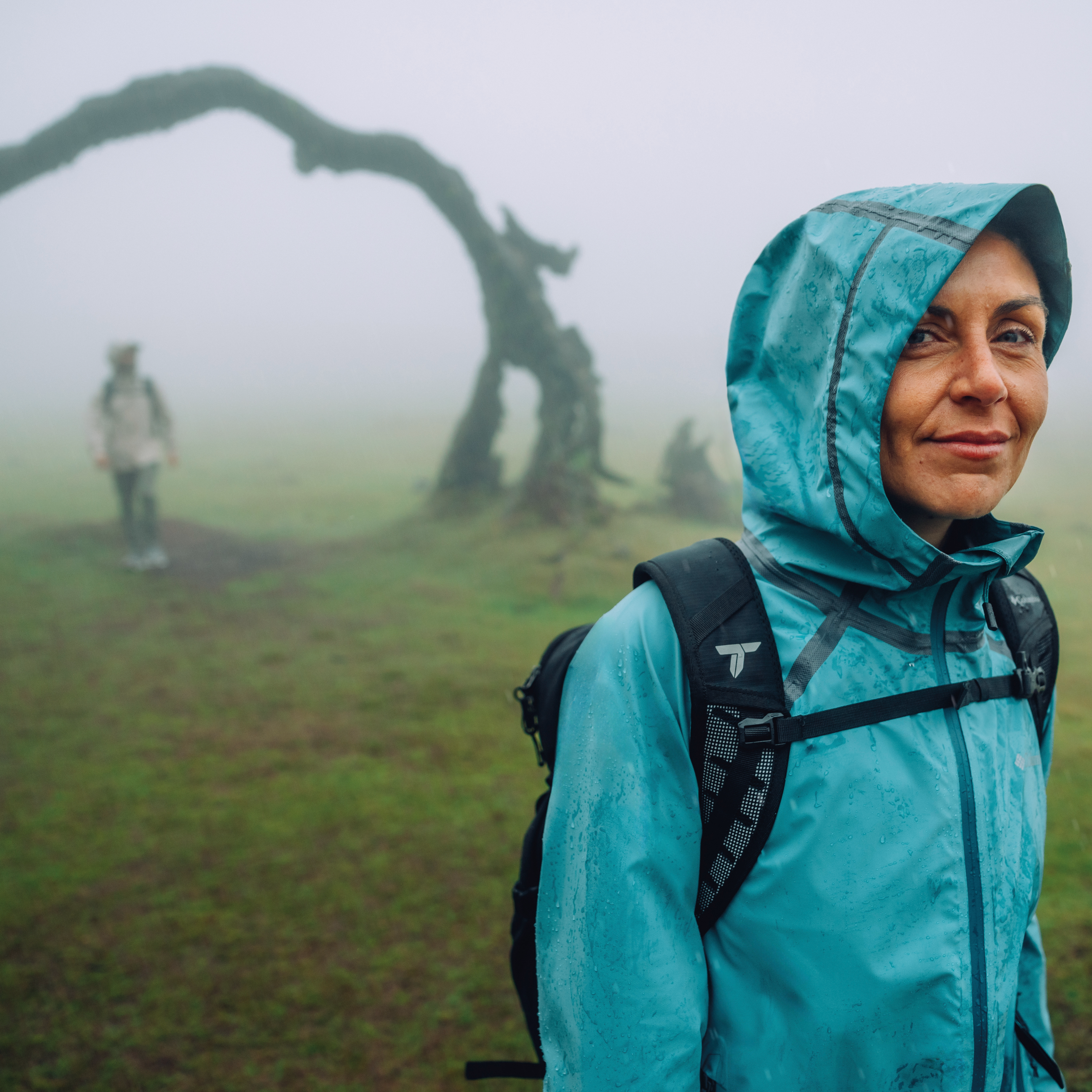 Woman wearing a Columbia Women's Reign No Shine Outdry Extreme Waterproof Jacket River Blue 364 2116293 in a foggy landscape