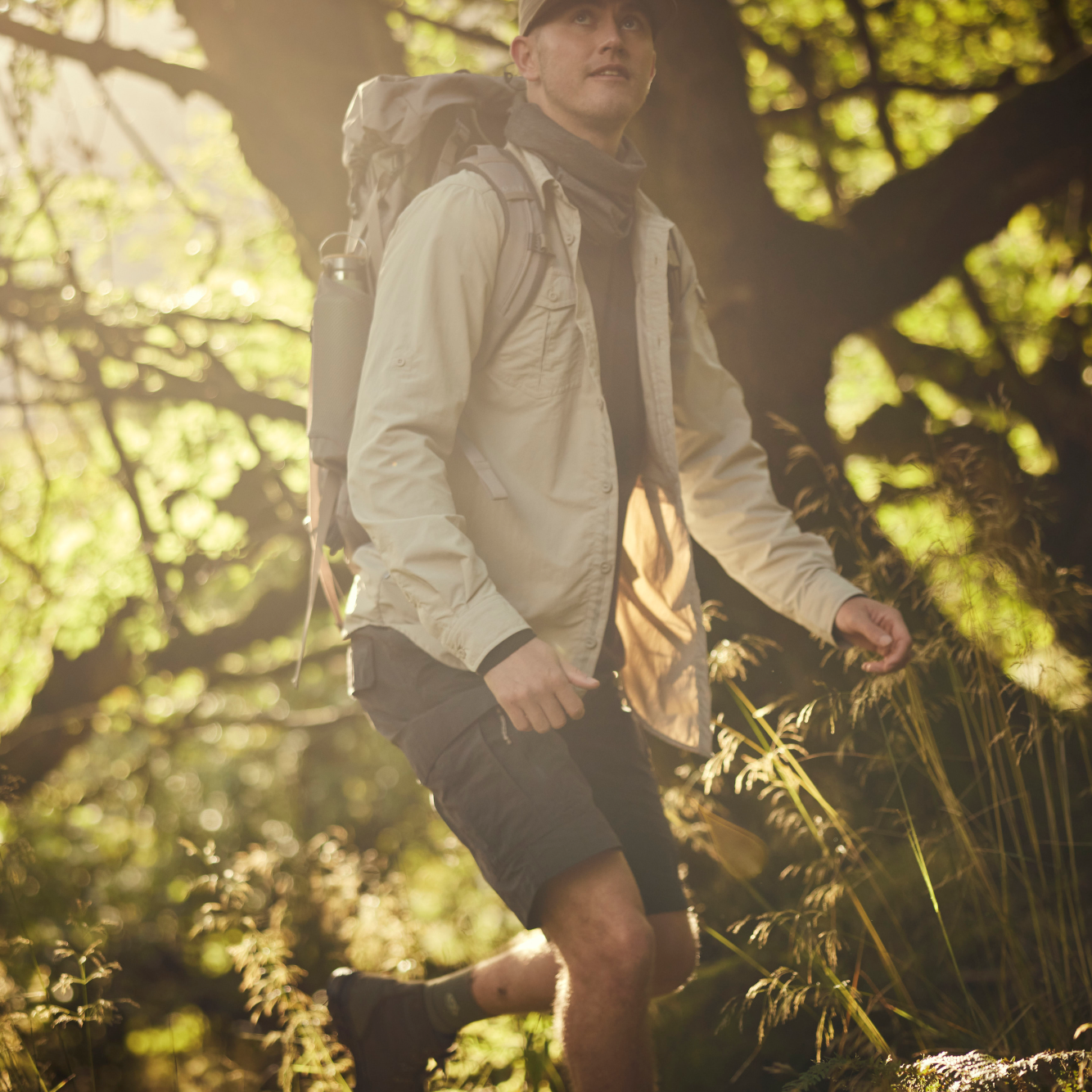 Man hiking through a forest with backpack and jacket wearing Craghoppers Men's NosiLife III Cargo Shorts 10.5 inch Black Pepper 7J8 CMJ651