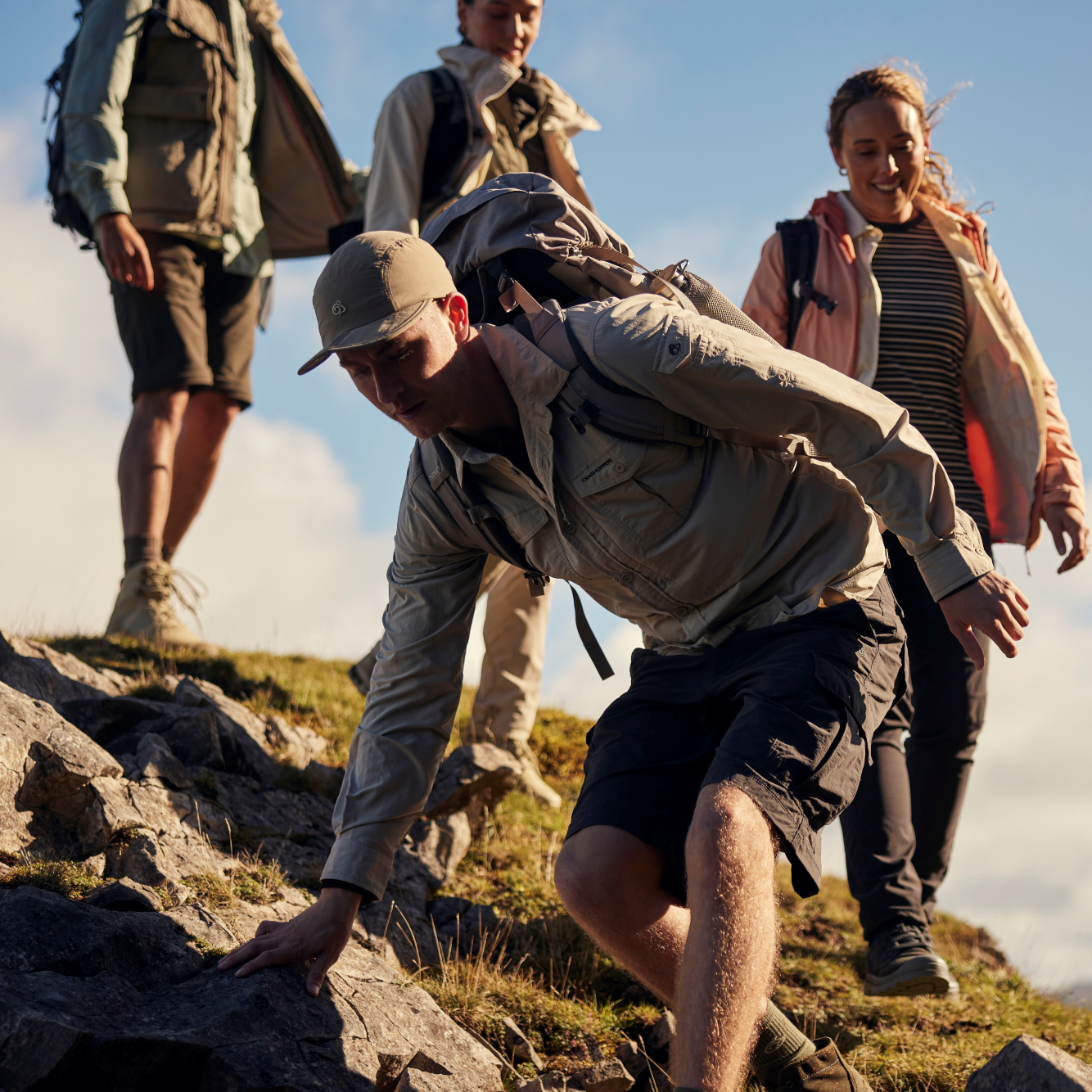 Group of people hiking on a mountain with clear skies. Man wearing Craghoppers Men's NosiLife III Cargo Shorts 10.5 inch Black Pepper 7J8 CMJ651