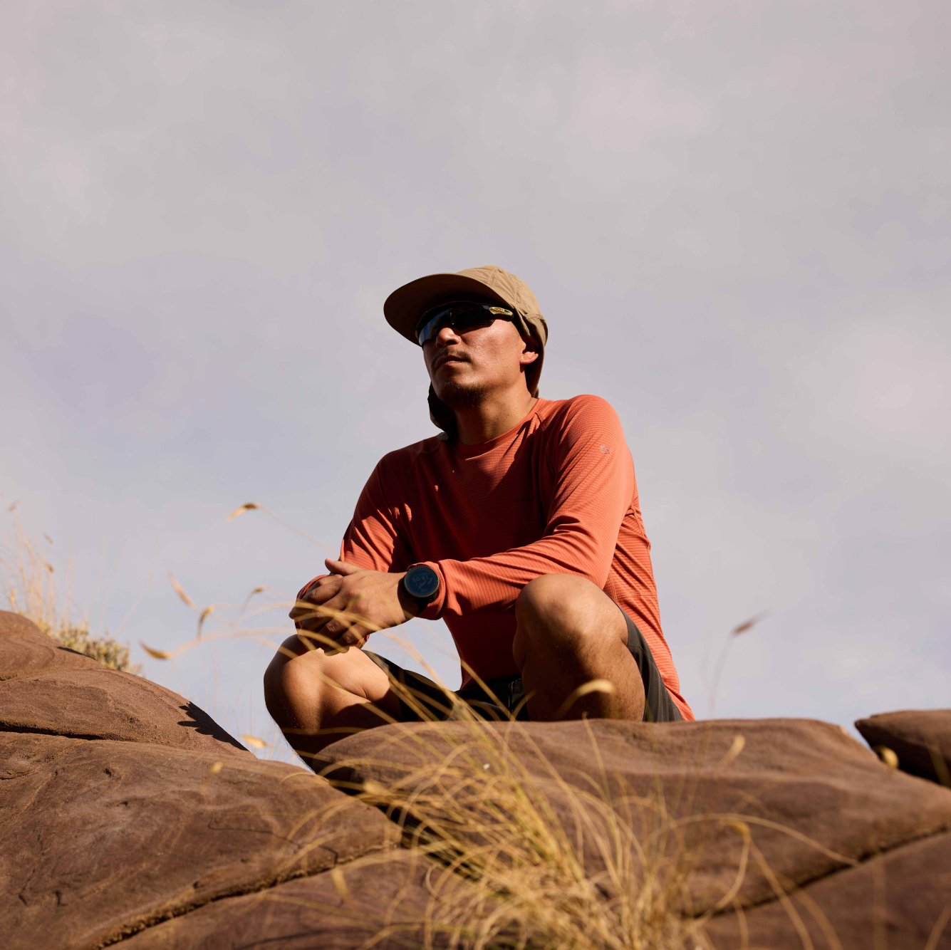 Man wearing Craghoppers Unisex Nosilife Desert III Sun Hat Pebble 695 CMC132 kneeling down on some rocks