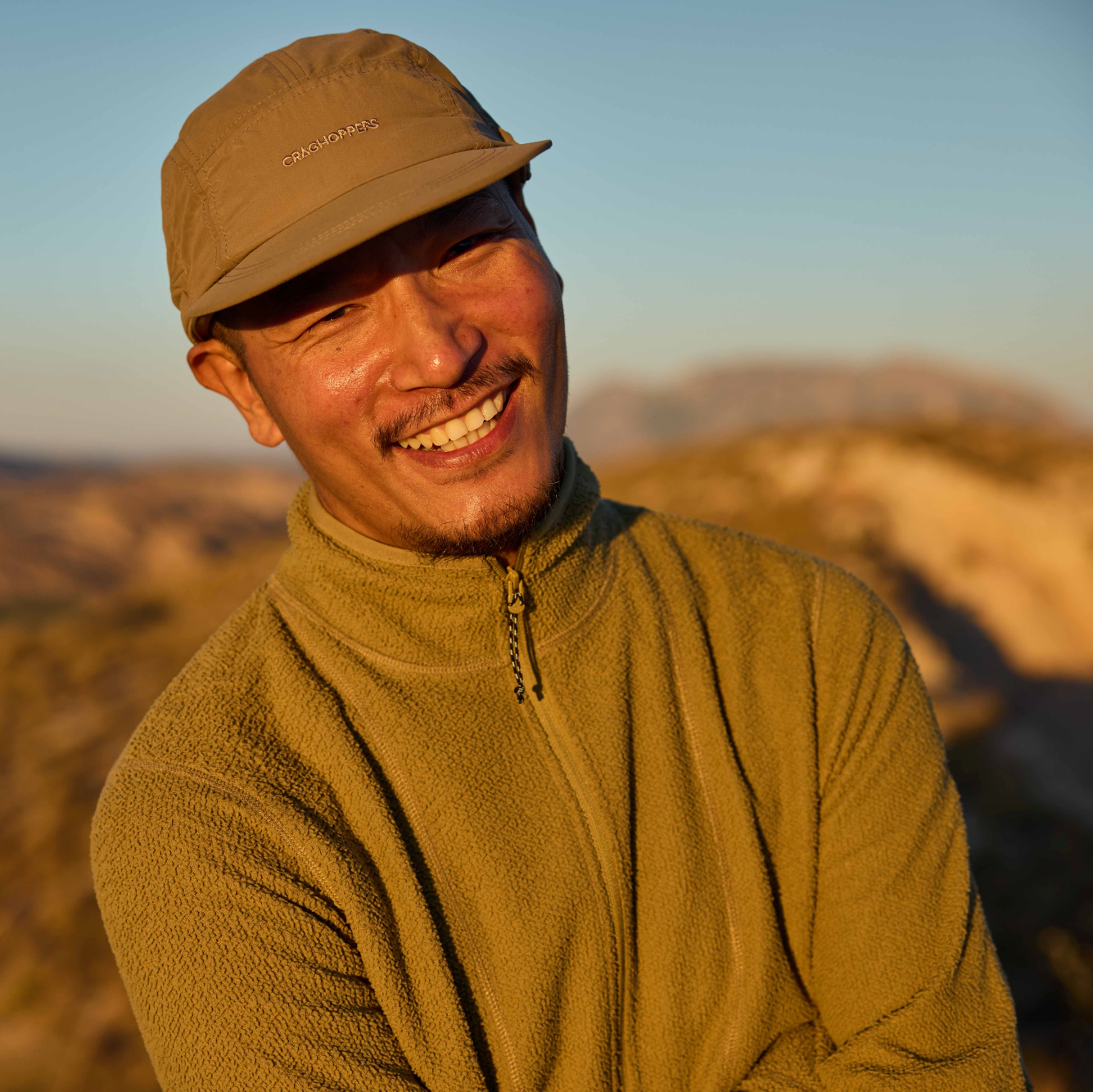 Man wearing Craghoppers Unisex Nosilife Desert III Sun Hat Pebble 695 CMC132 smiling in the setting sun