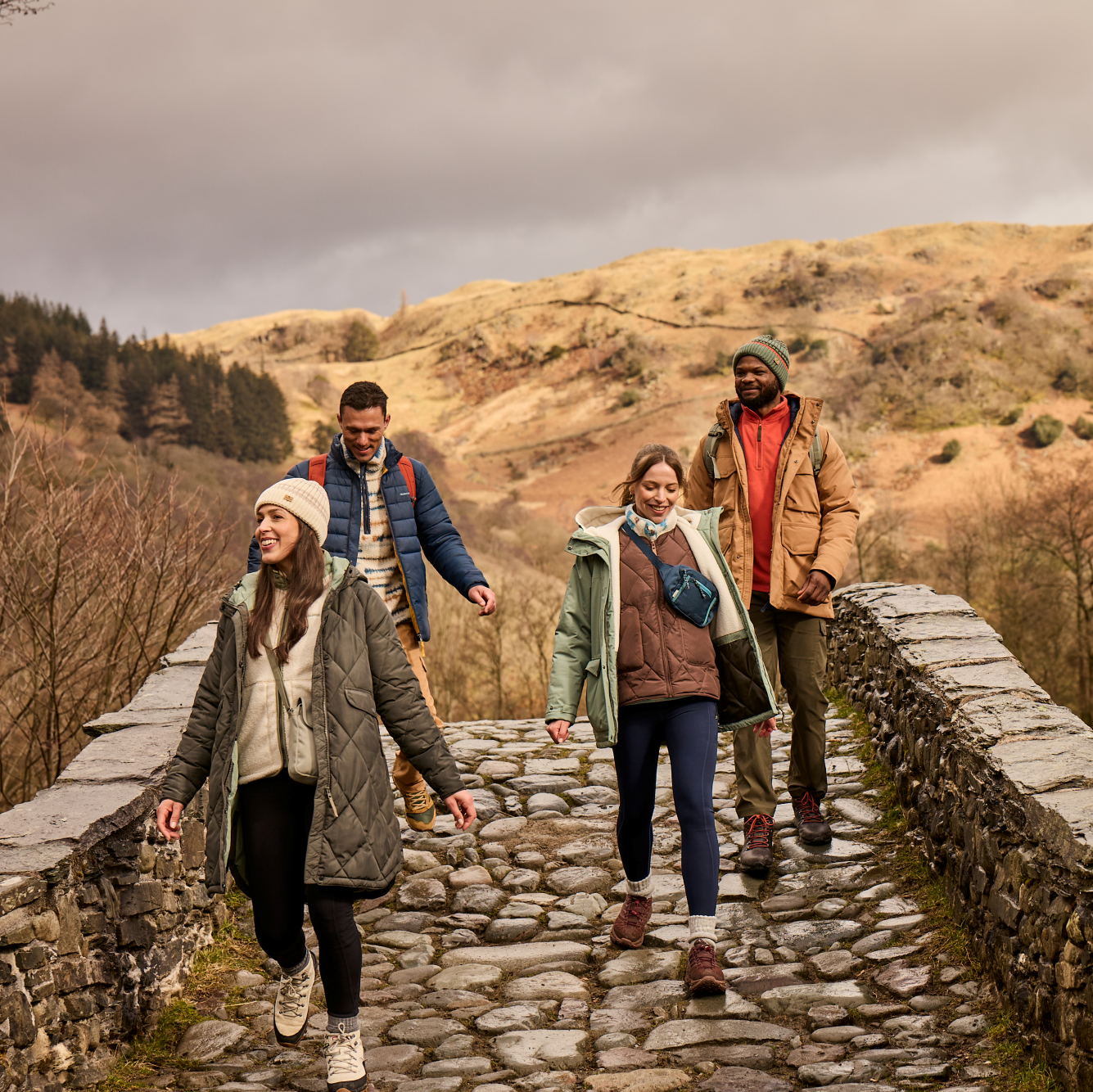 Woman wearing Craghoppers Women's Kiwi Pro Leggings Blue Navy 7V1 CWJ1335 walking across a stone bridge with friends