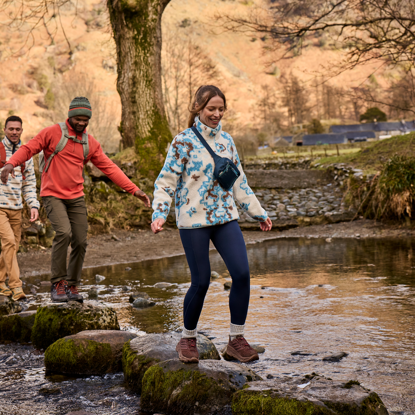 Woman wearing Craghoppers Women's Kiwi Pro Leggings Blue Navy 7V1 CWJ1335 crossing a river on stepping stones