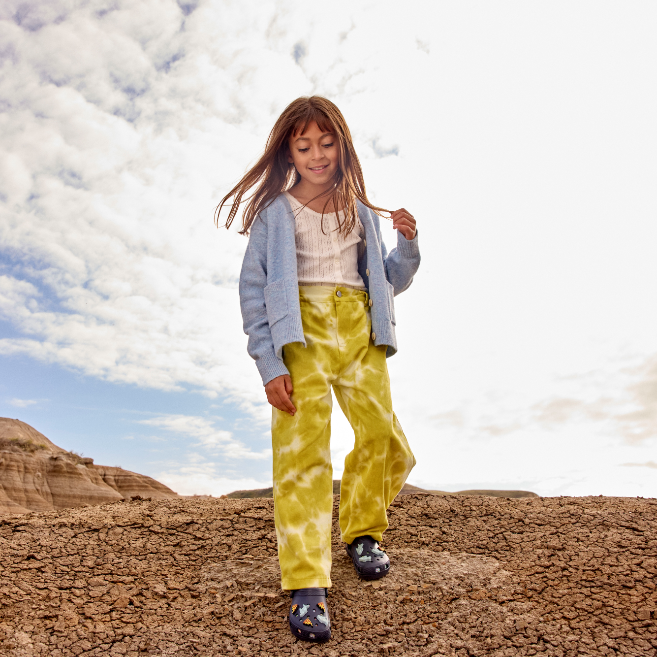 Young girl wearing Crocs Classic Clogs Junior Navy 410 206991 walking in a desert setting