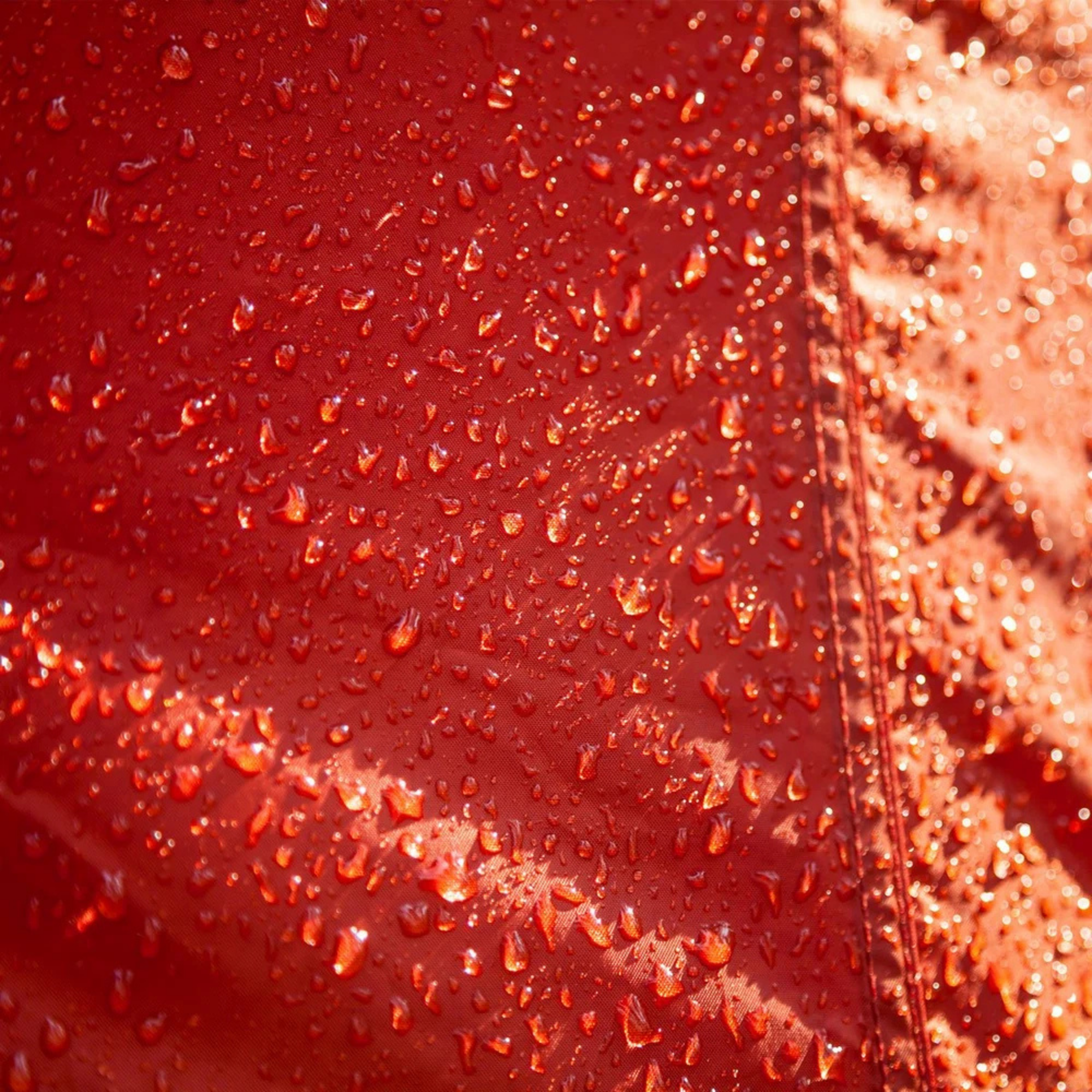 Close-up of a red tent surface with water droplets