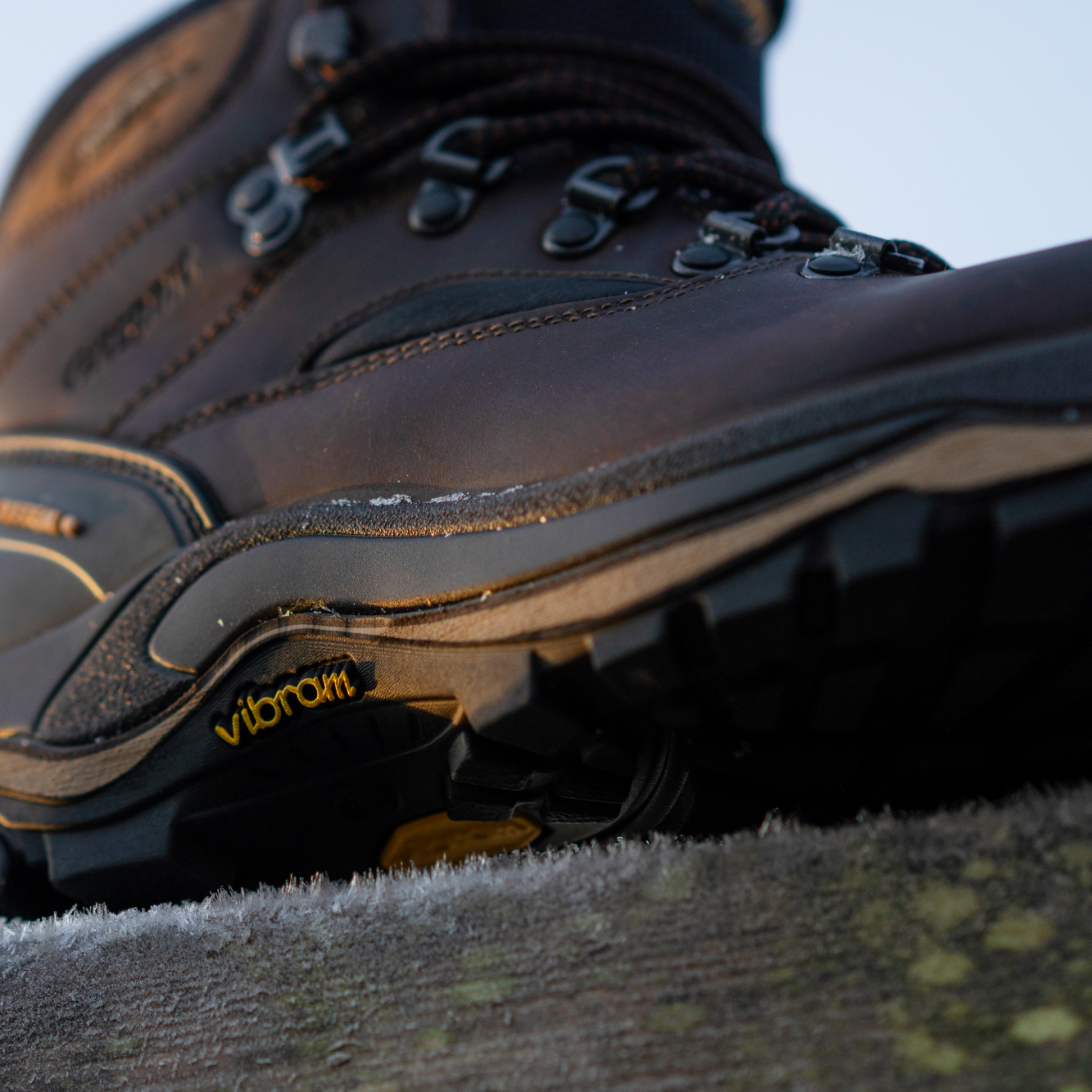 Shot of Grisport Men's Quatro Waterproof Hillwalking Boots Brown CMG614 from below showing the vibram logo and side profile of the boot sitting on a picnic table