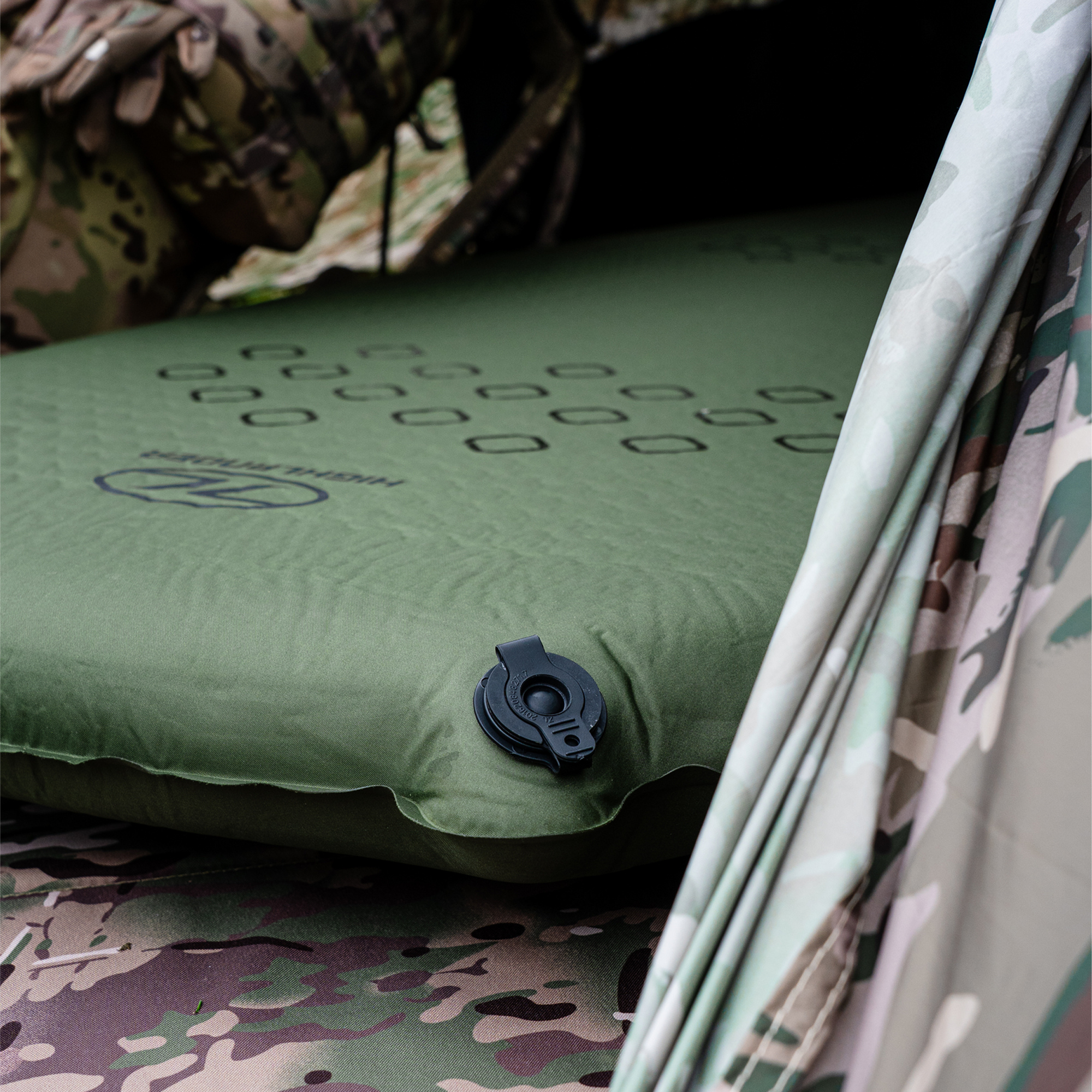 Highlander Self Inflating Kip Sleeping Mat 75mm Olive Green SM132-75 in a tent on a camouflage-patterned background