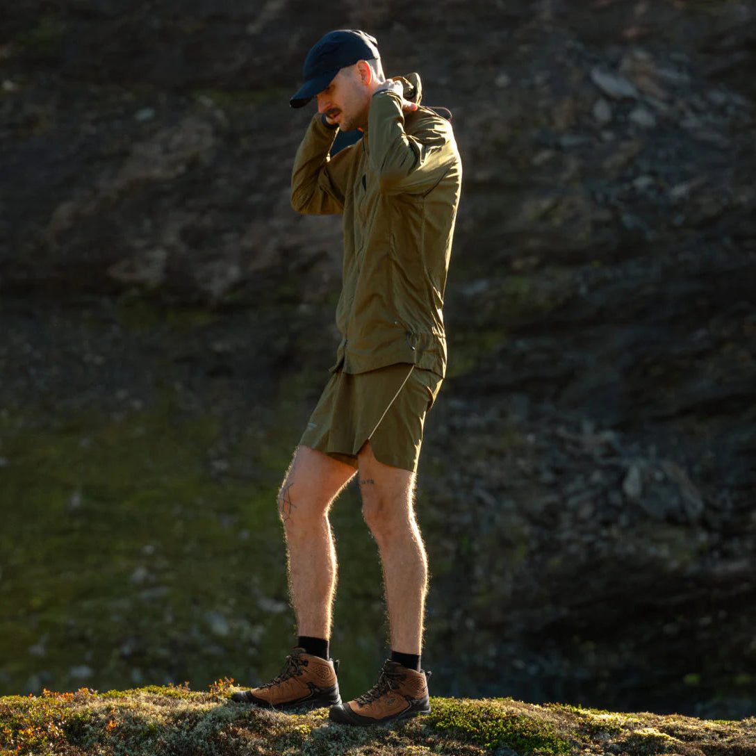 Man wearing Keen Men's Targhee IV Waterproof Mid Trail Boots Wide Fit Bison Black 1029002 outside on a mountain trail