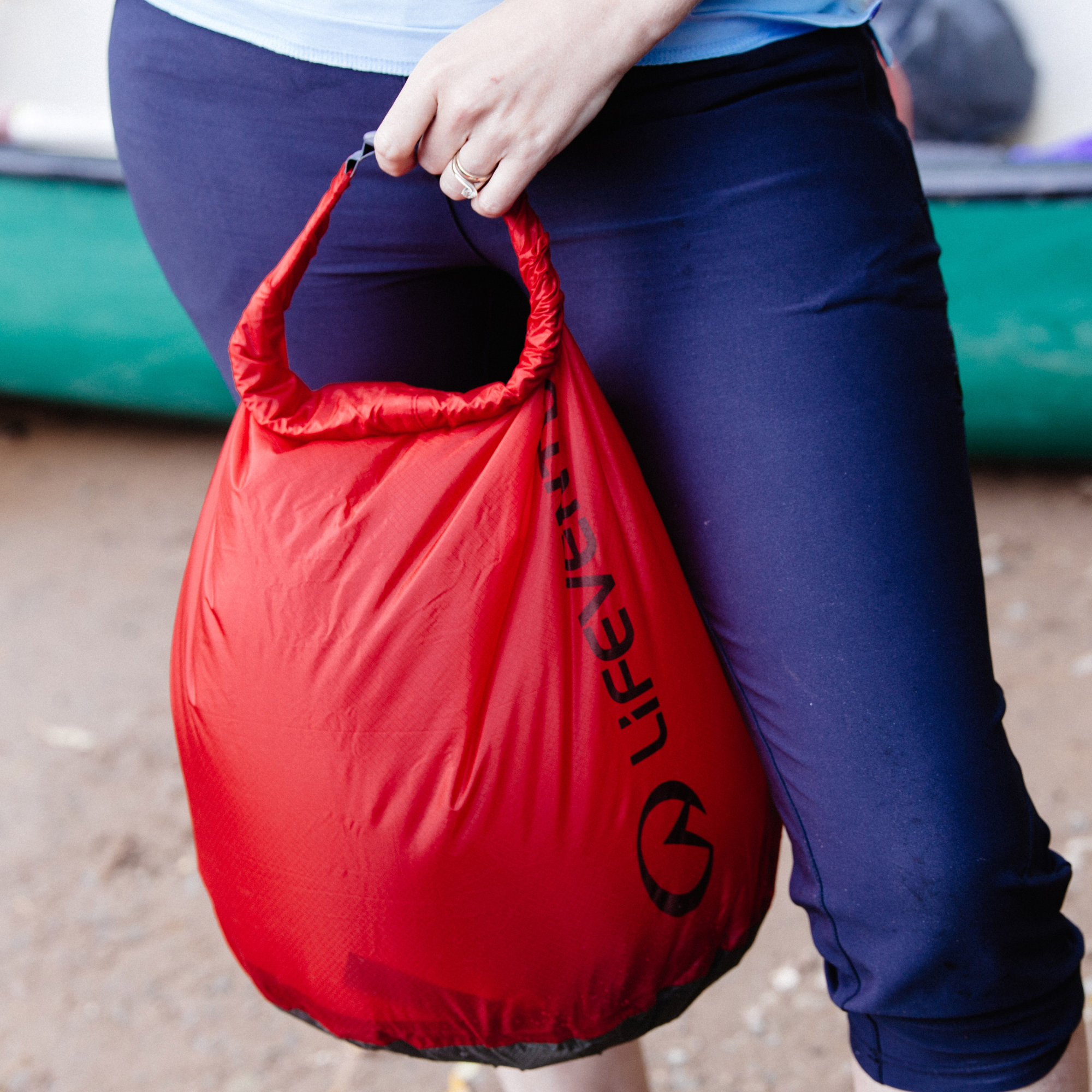 Person holding a red Lifeventure Ultralight Dry Bag with a blurred background