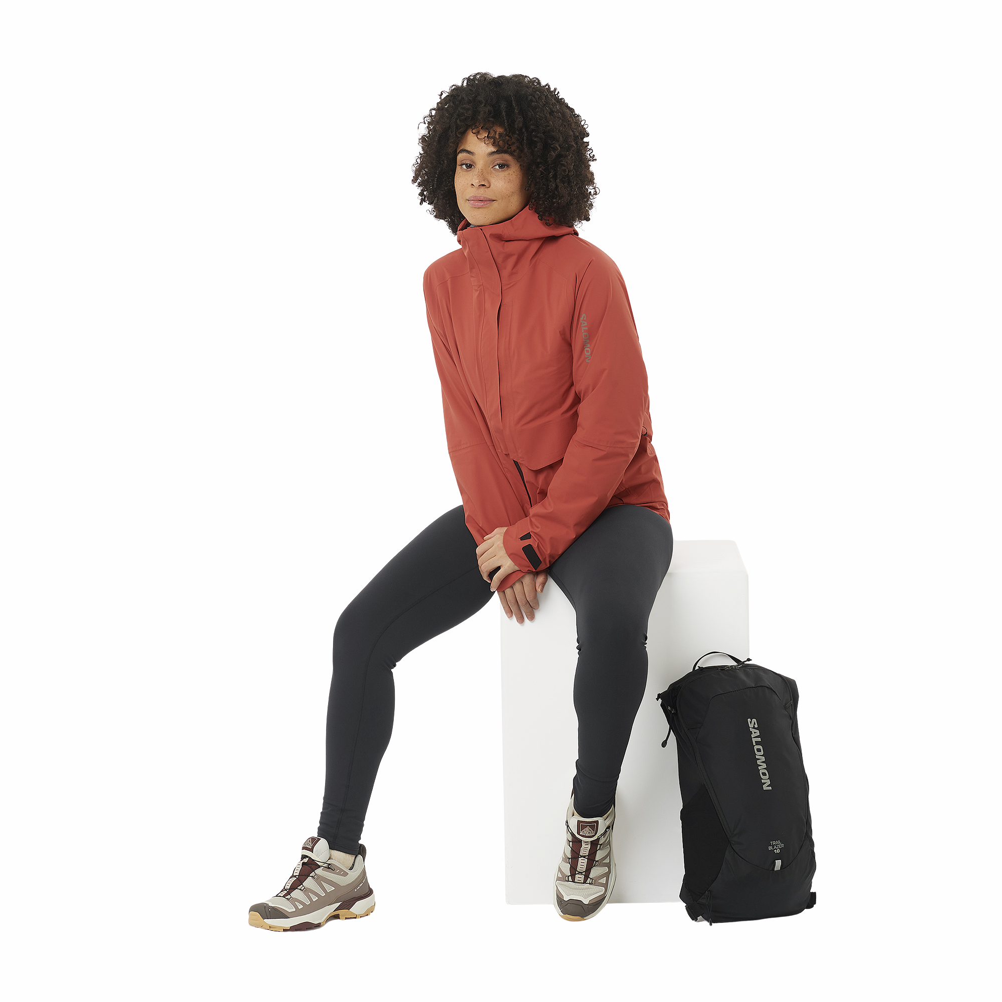Woman sitting with a Salomon Trailblazer 10L Daysack Black Alloy LC2182900 on the ground beside her