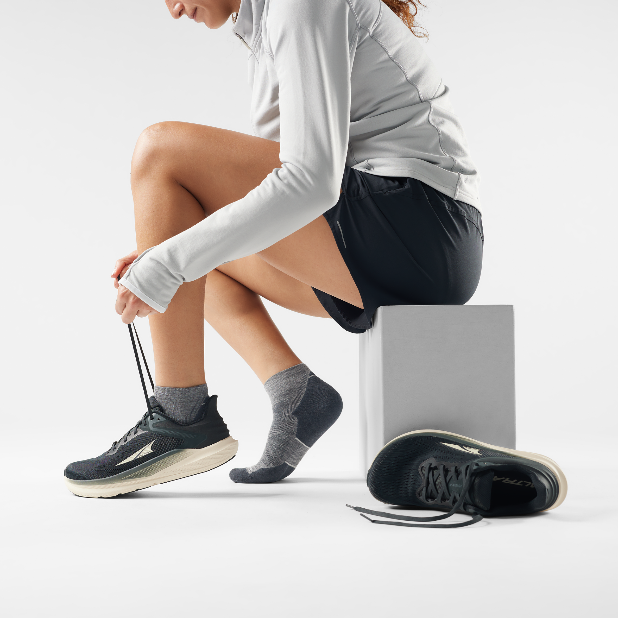 Person tying shoelaces with athletic shoes on a plain background wearing Smartwool Men's Targeted Cushion Ankle Length Run Socks Medium Grey 052 SW001661