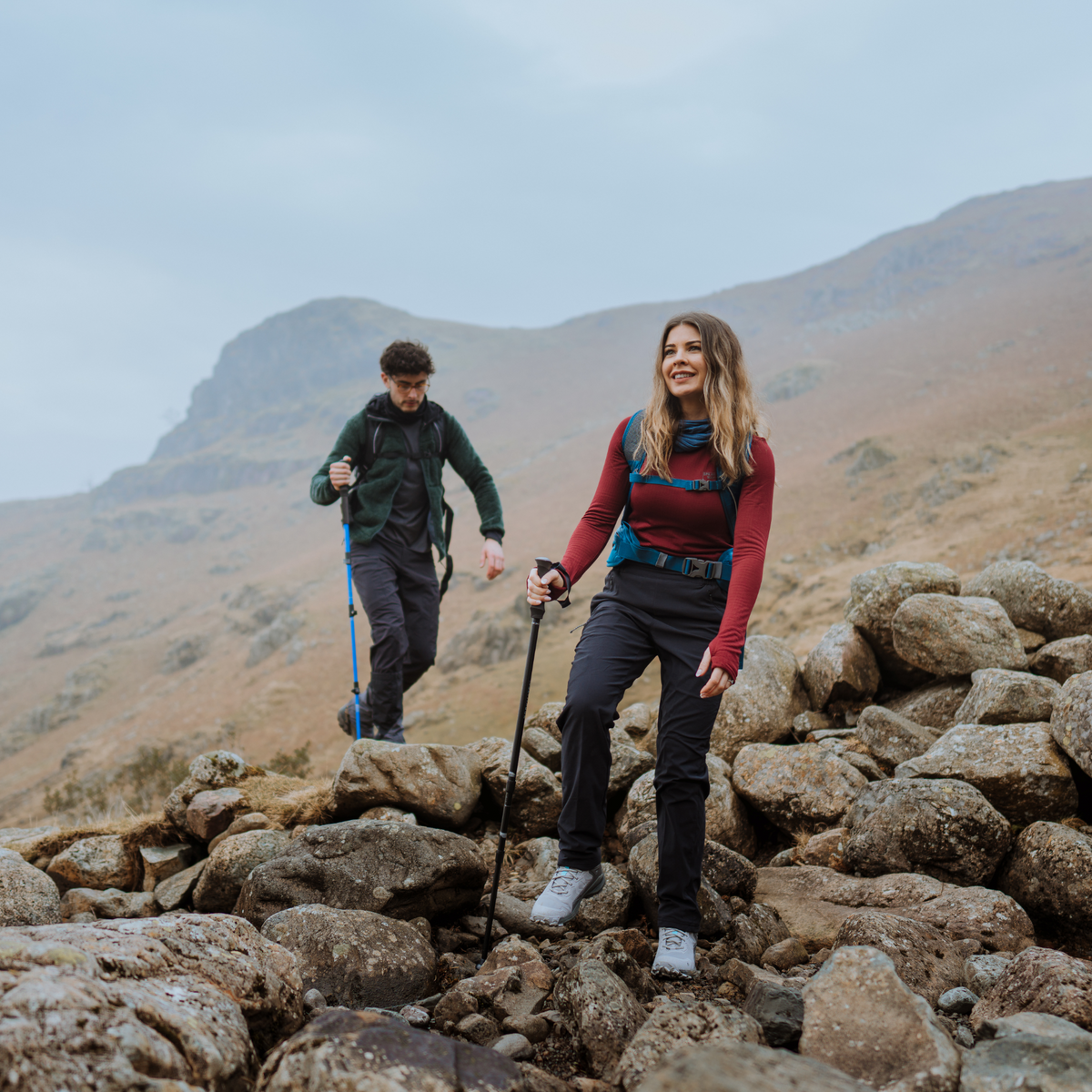 Two hikers on a rocky mountain top with misty mountains in the background. Woman using Trekmates Hiker Shock Single Pole Black TM-008705