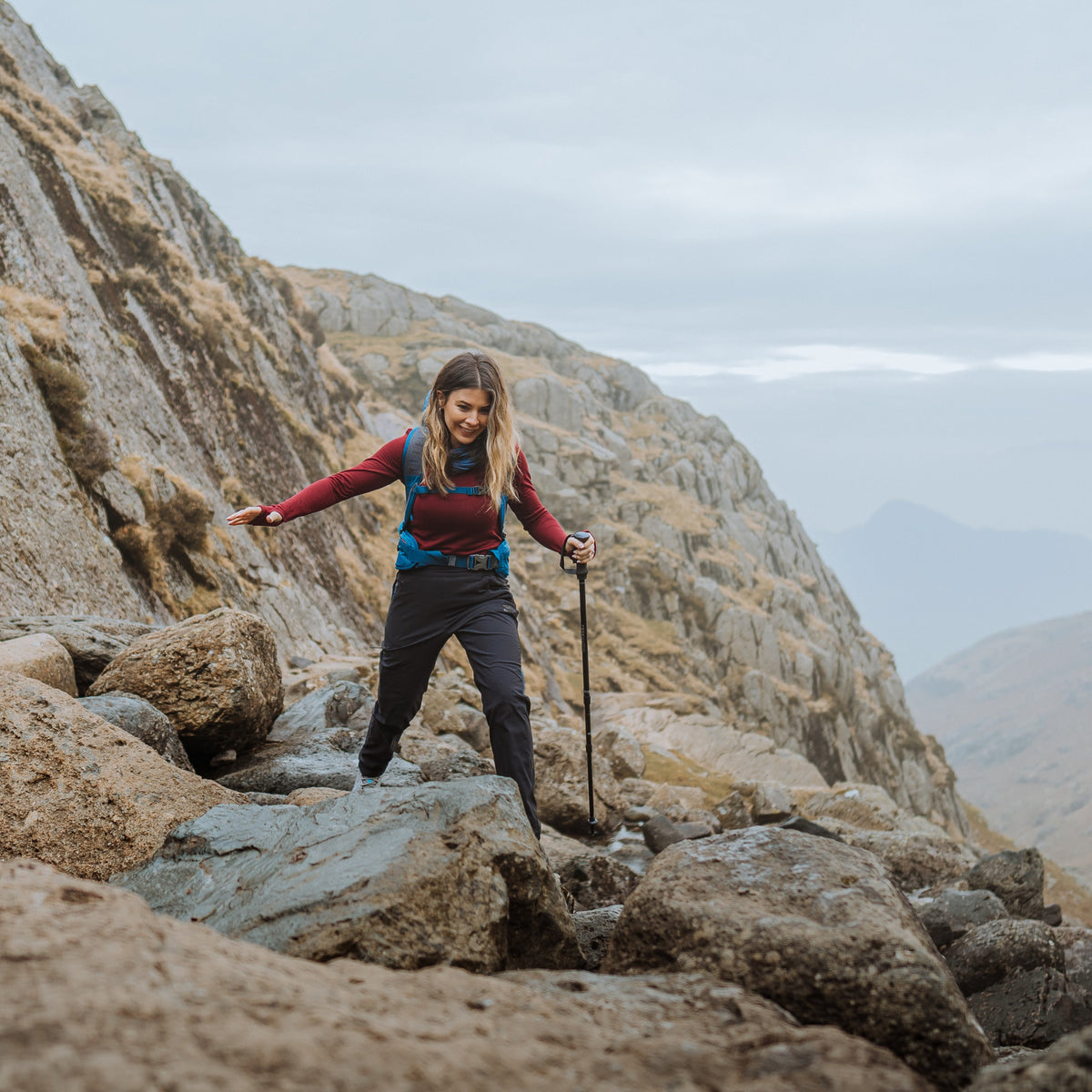 Person hiking on rocky terrain with a backpack and Trekmates Hiker Shock Single Pole Black TM-008705