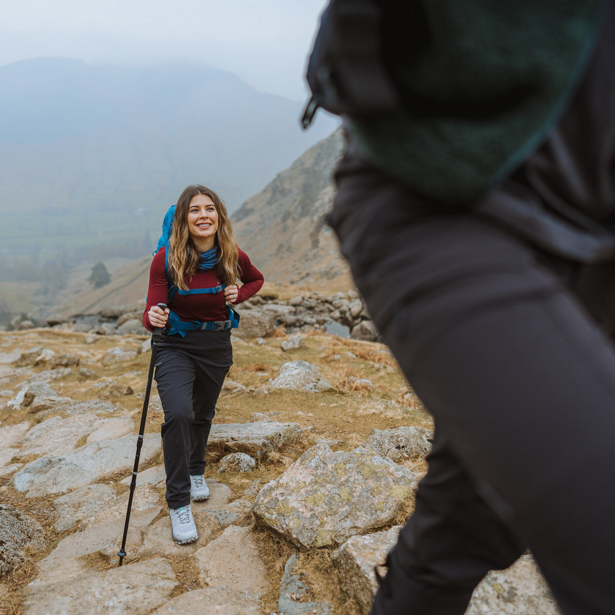 Woman hiking up a mountain with a Trekmates Hiker Shock Single Pole Black TM-008705