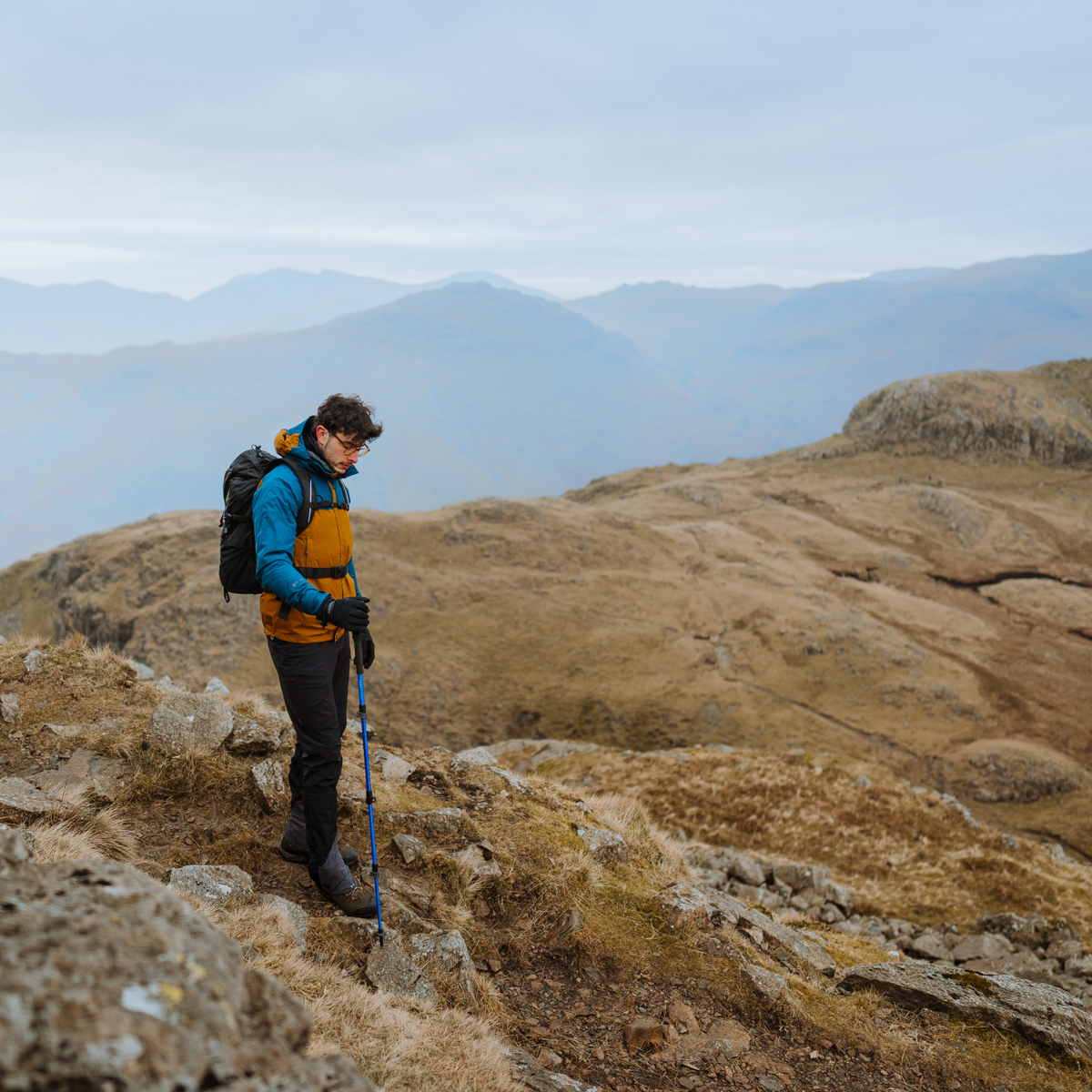 Hiker on a mountain trail with backpack and Trekmates Trekker Compact Single Pole Cobalt TM-008702
